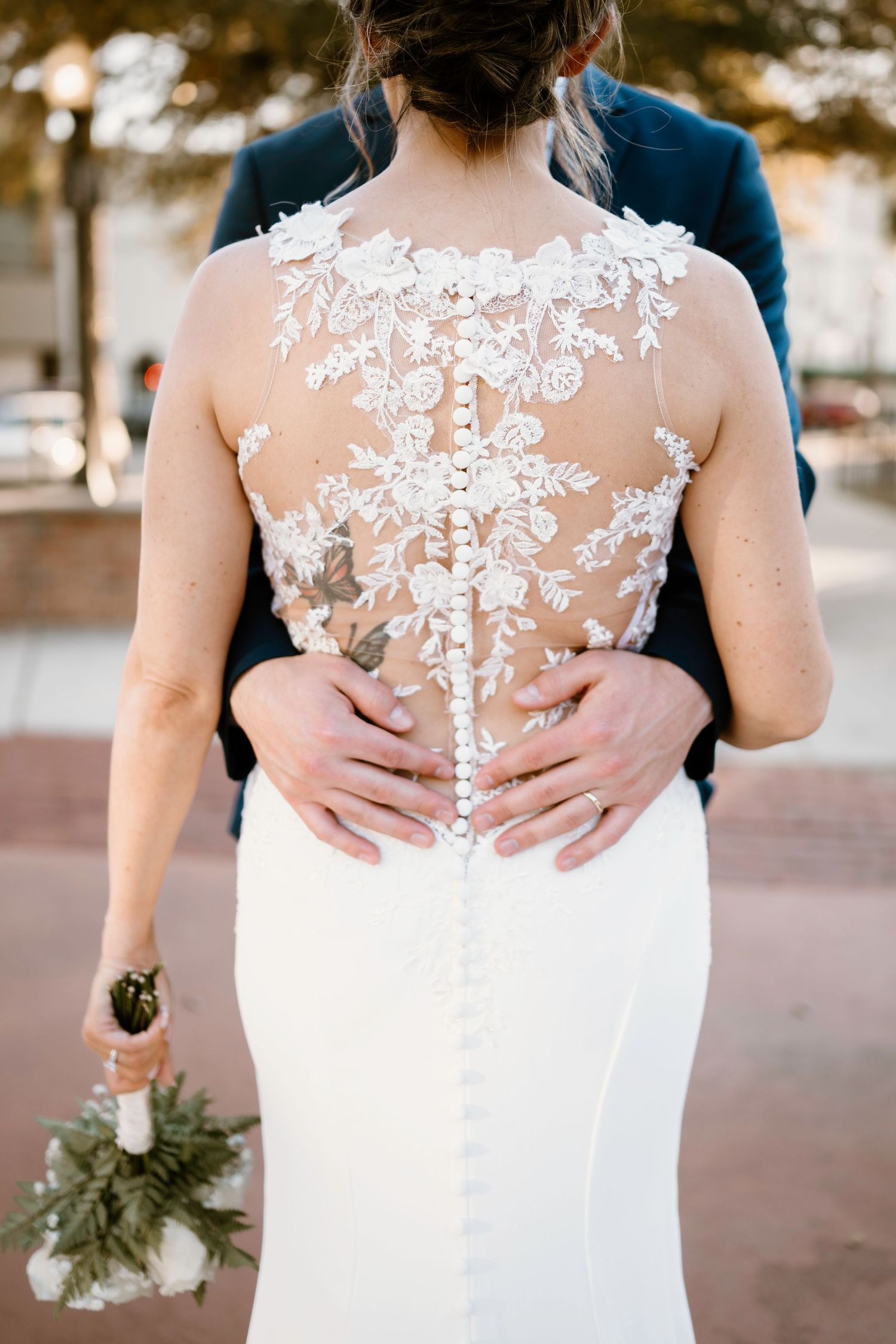 Detail shots of intricate white lace back design on wedding dress with floral appliques.