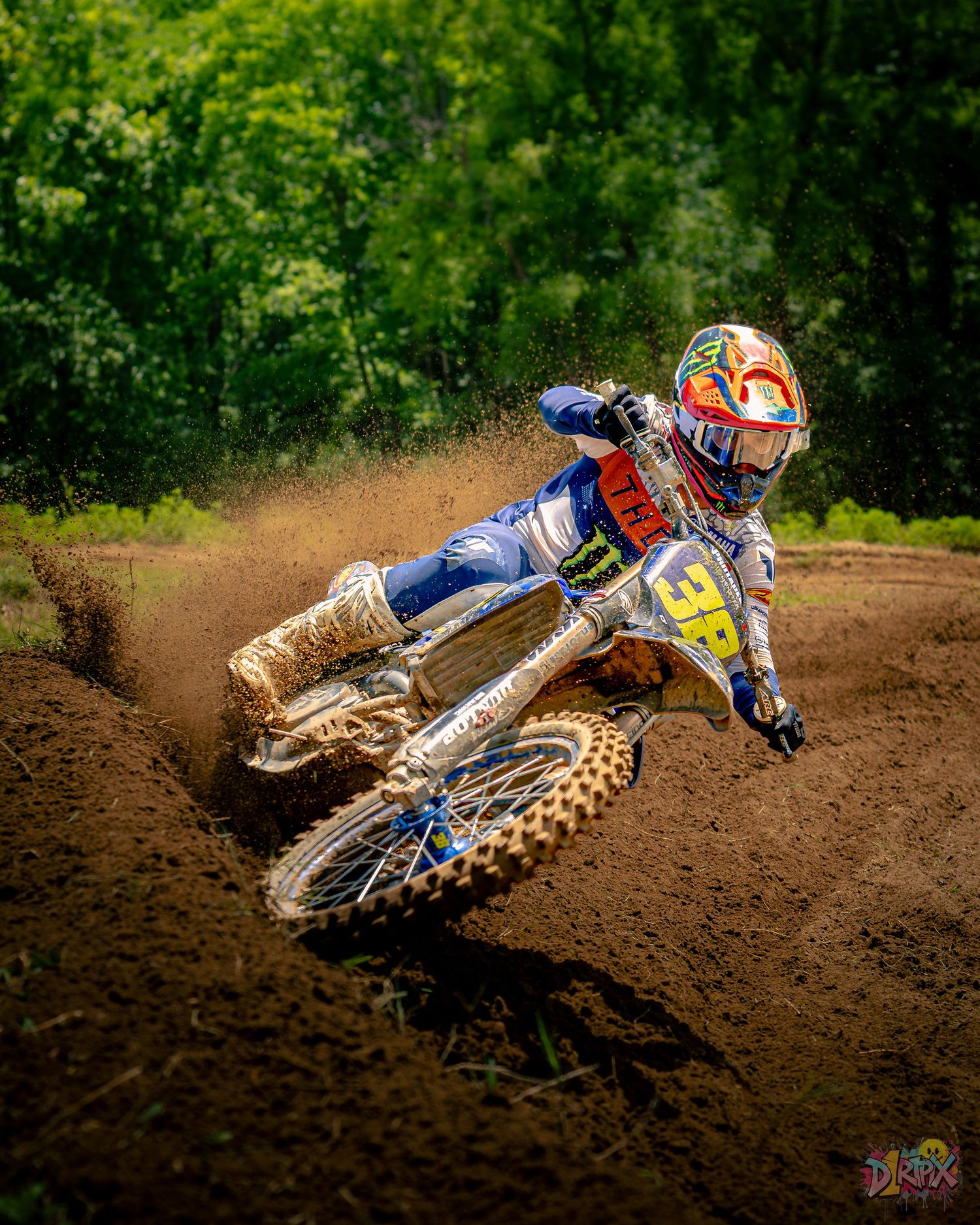 Sequence of a motocross rider performing a high-speed turn through a dirt track corner, kicking up dust and debris.