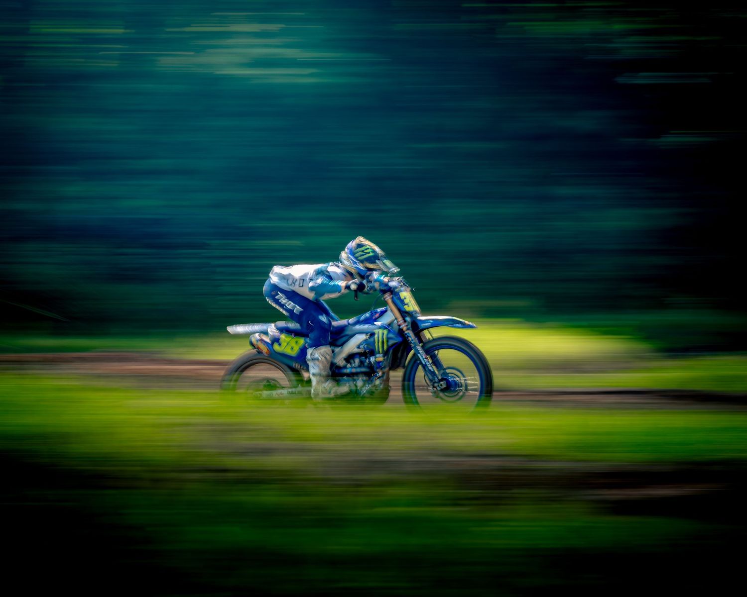 Racing motorcycle speeding through a blurred motion background creating a dynamic action shot with green tones.