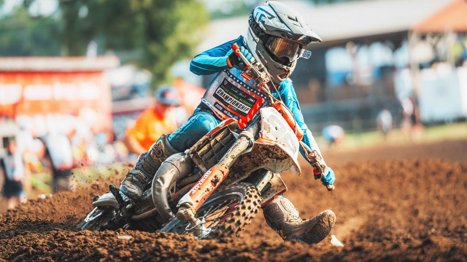 Motocross rider navigating muddy dirt track in blue gear and helmet during an outdoor racing competition.