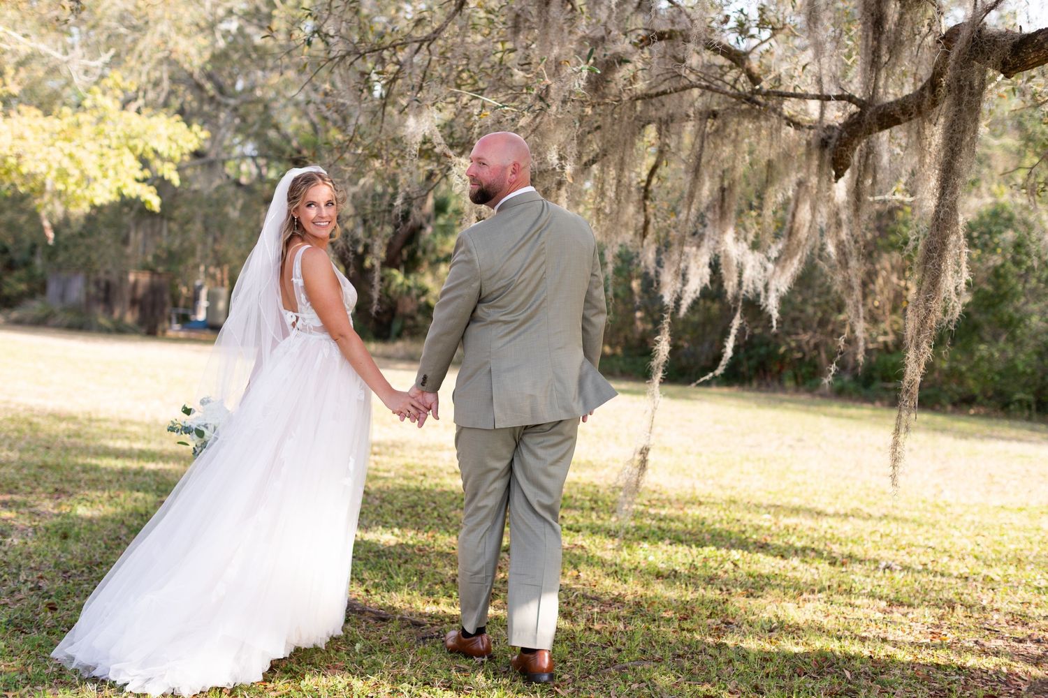 Wedding photography session beneath Spanish moss draped trees in natural sunlight.