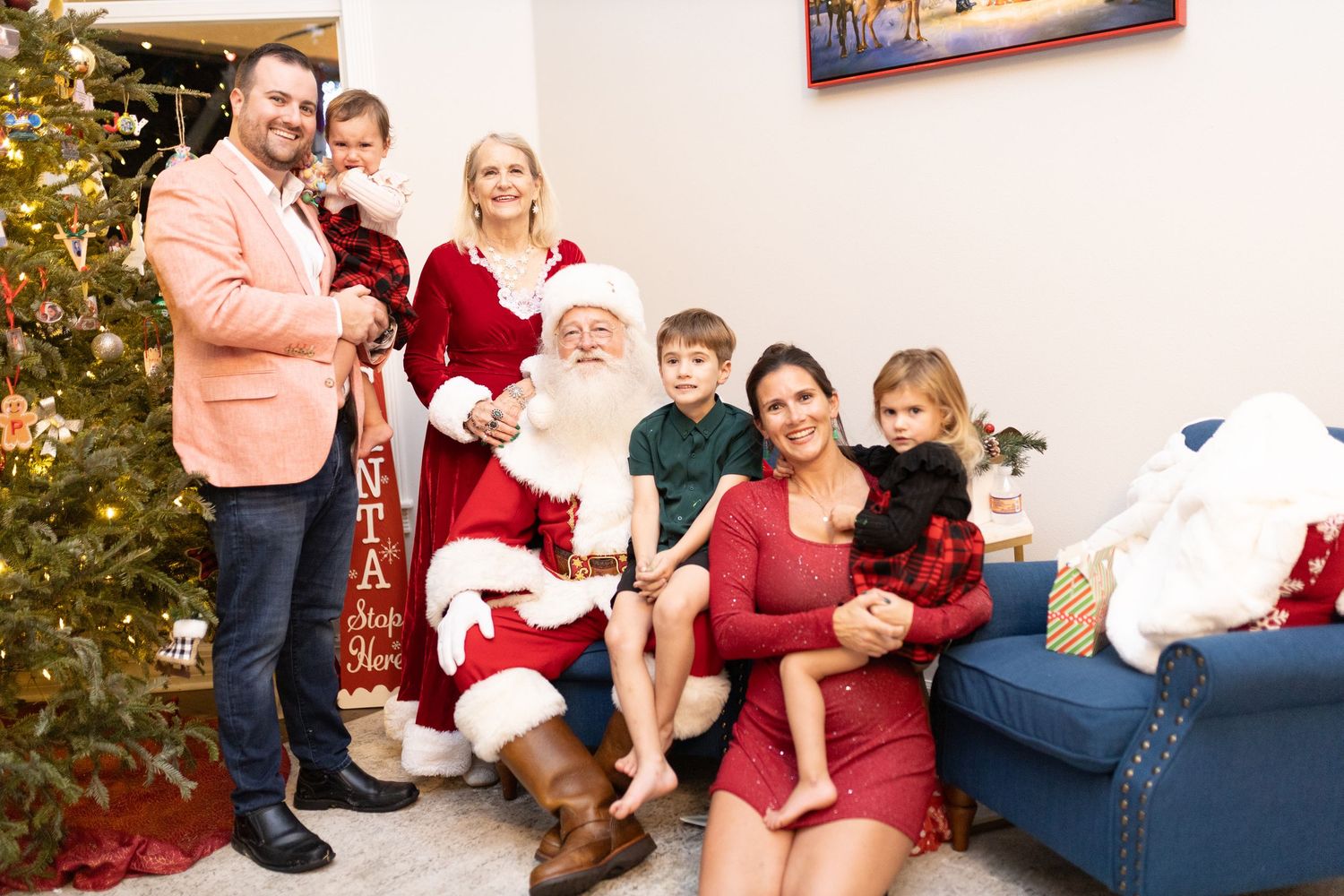 Christmas photo session with Santa Claus and family members wearing red and festive attire.
