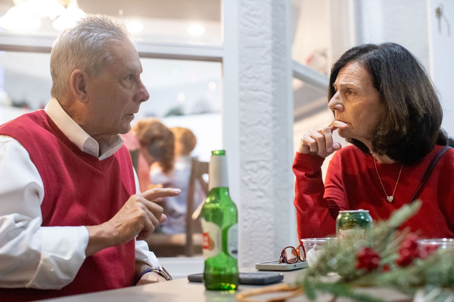 Two people having a conversation at a holiday dinner table with festive decorations.