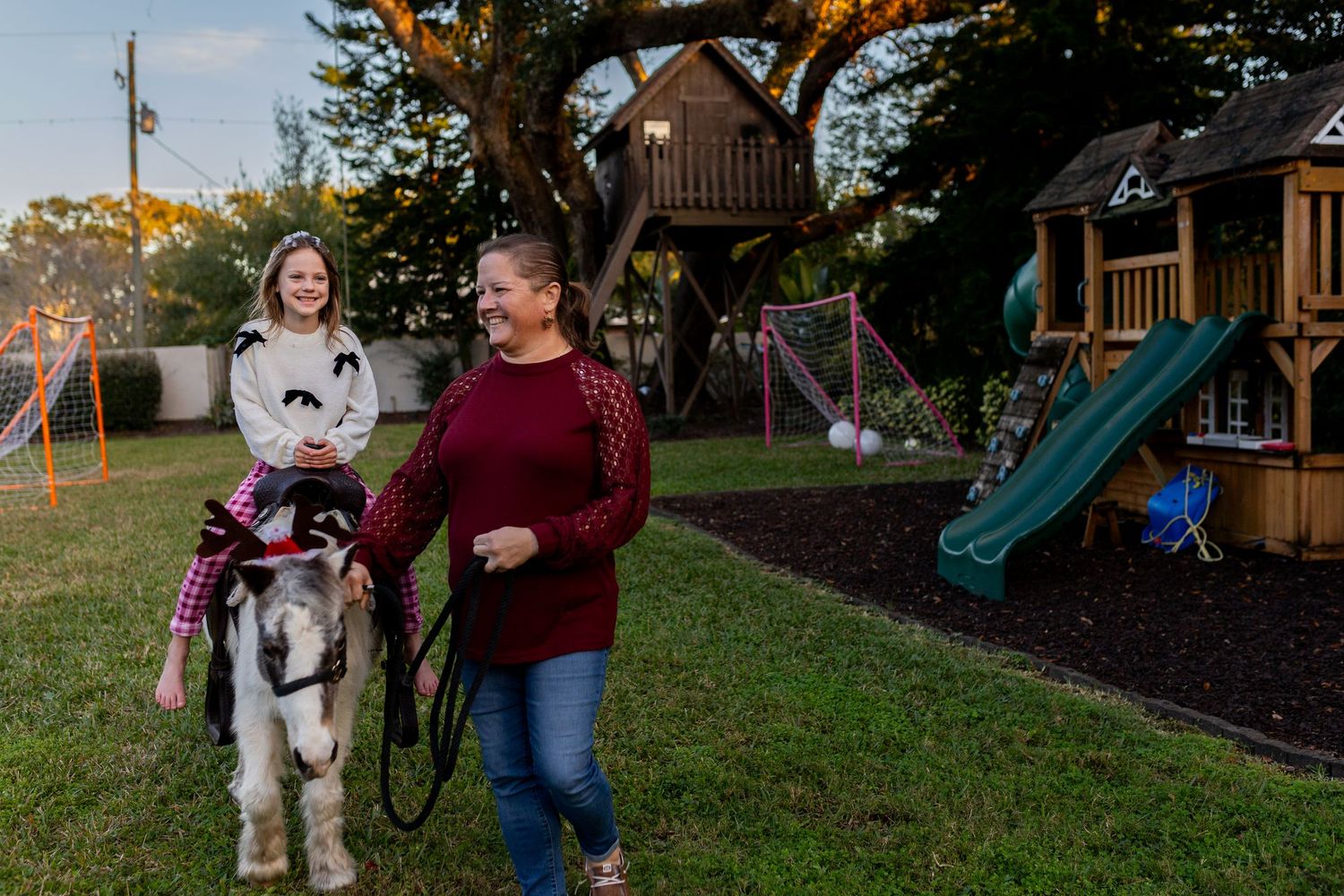Dog and person walking through backyard with playground visible.
