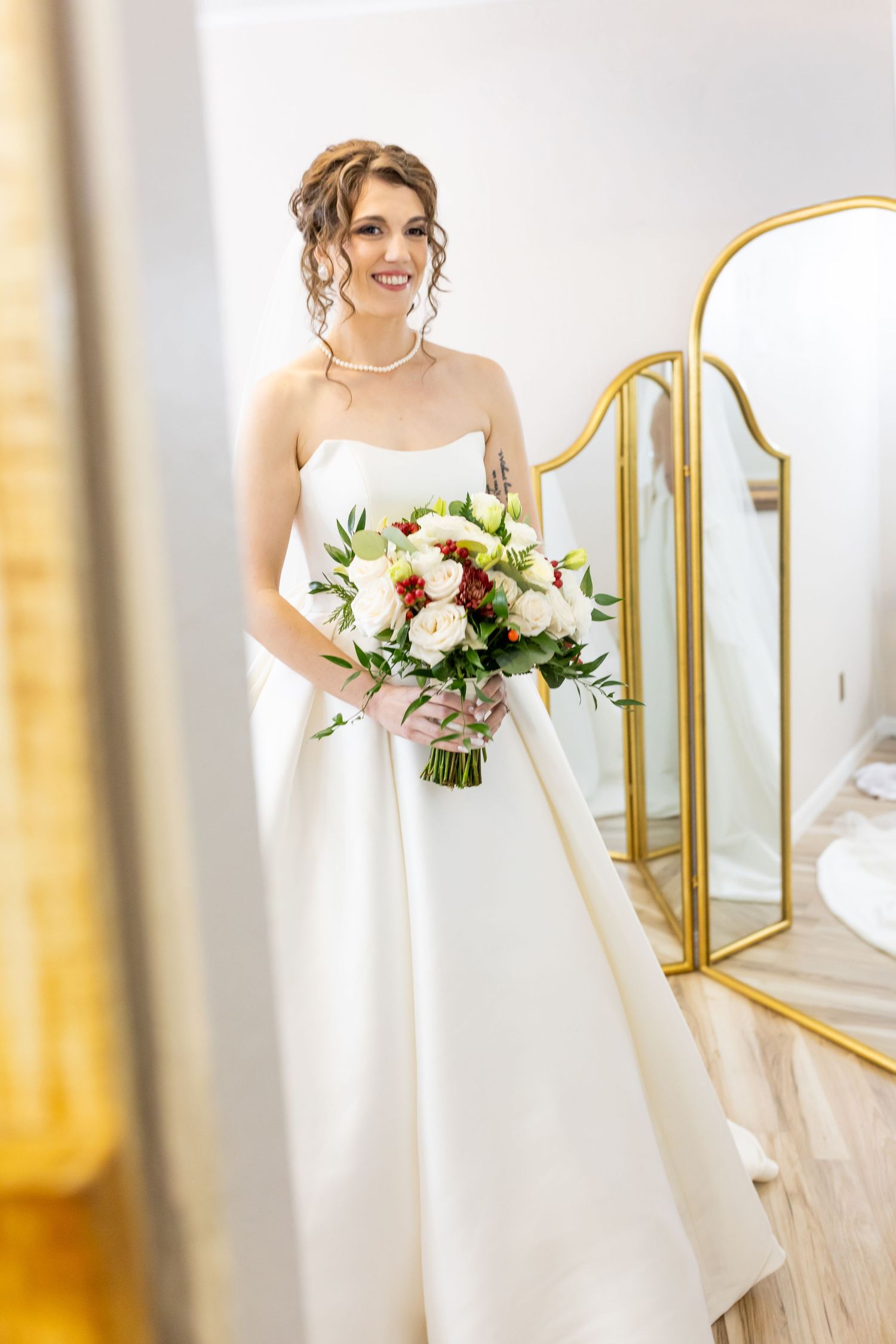 Elegant bridal portraits in white dress with bouquet against gold-framed mirrors.