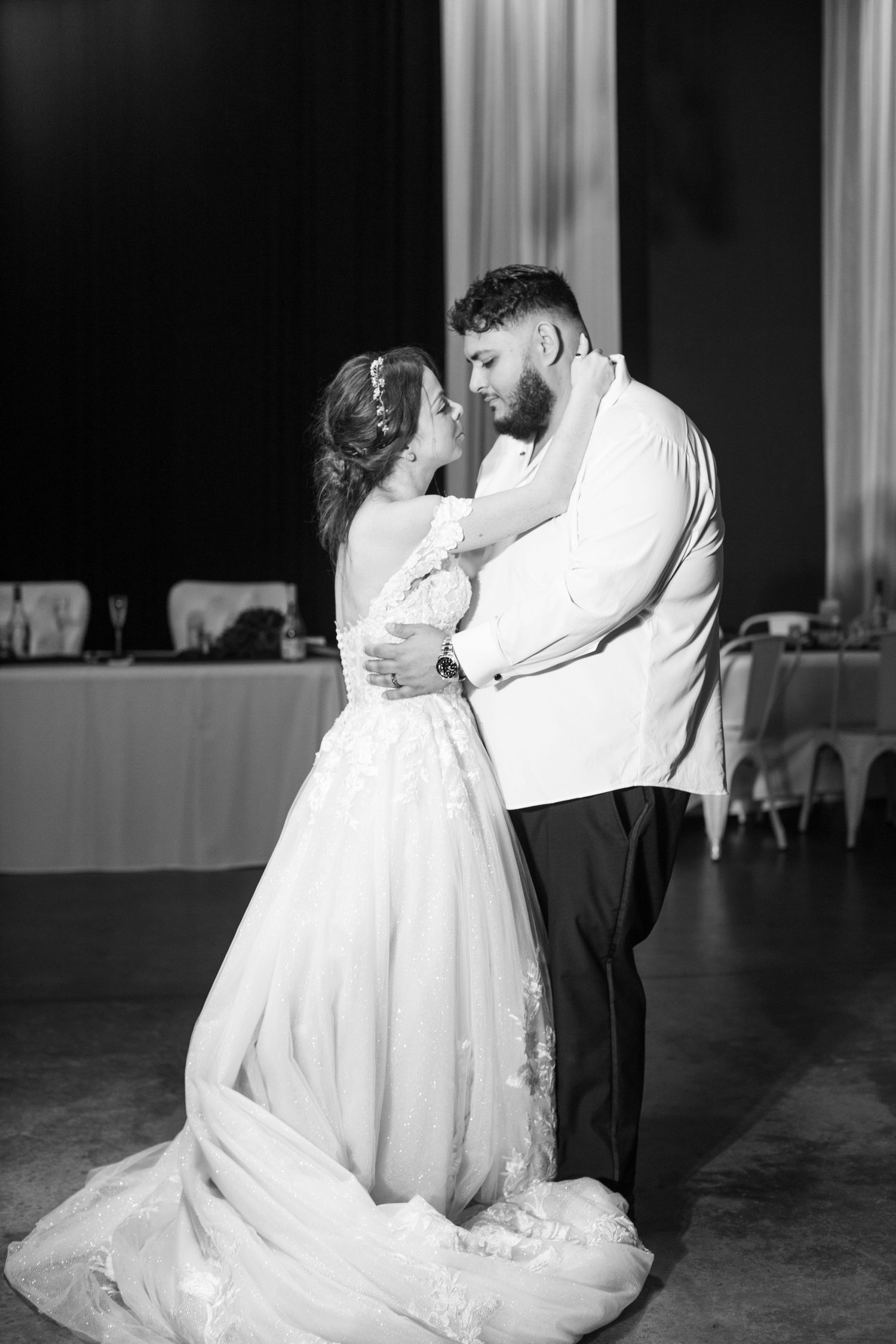 Black and white photo of bride and groom sharing first dance at wedding reception.