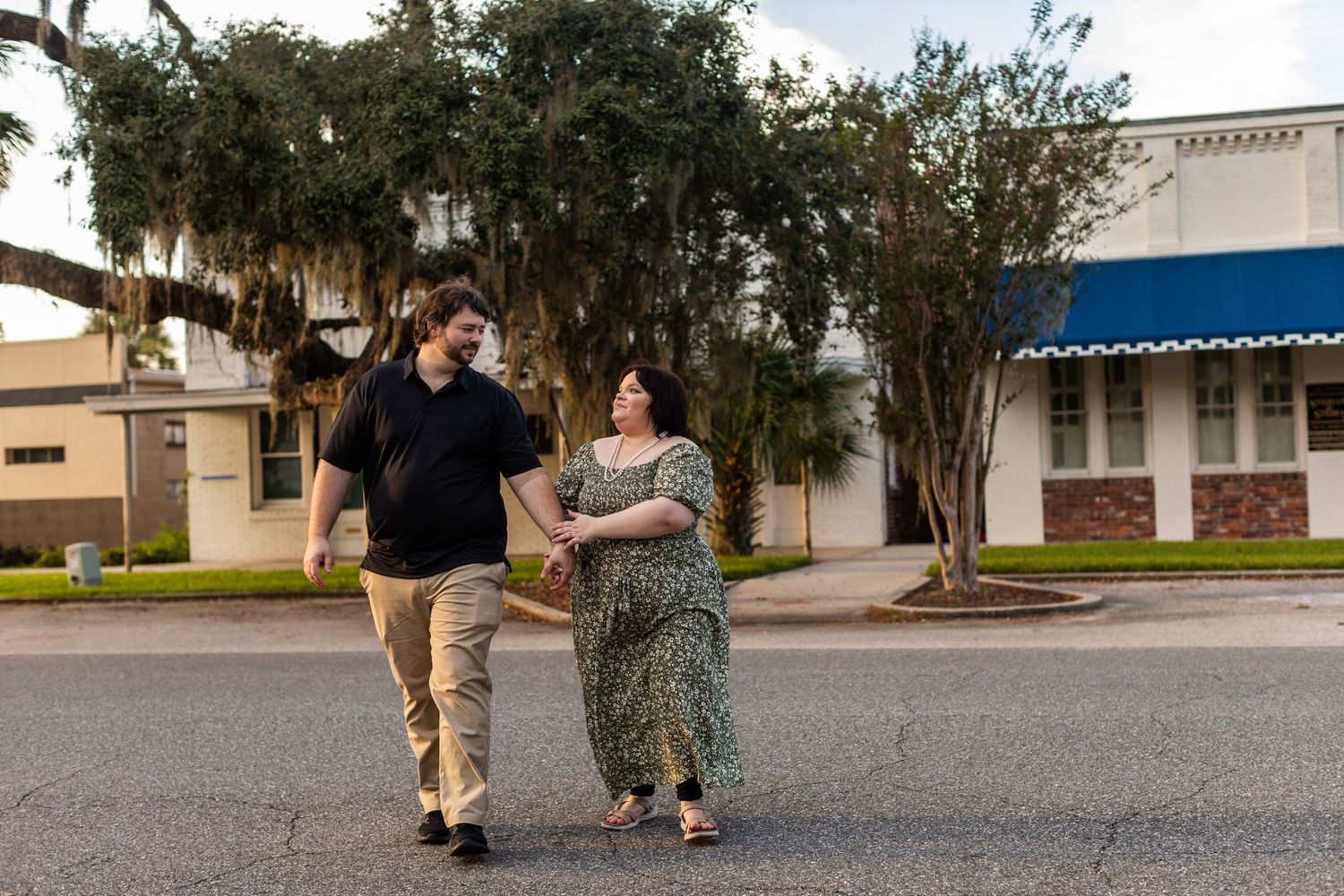 A couple shares a moment outside a classical building with trees in the background.
