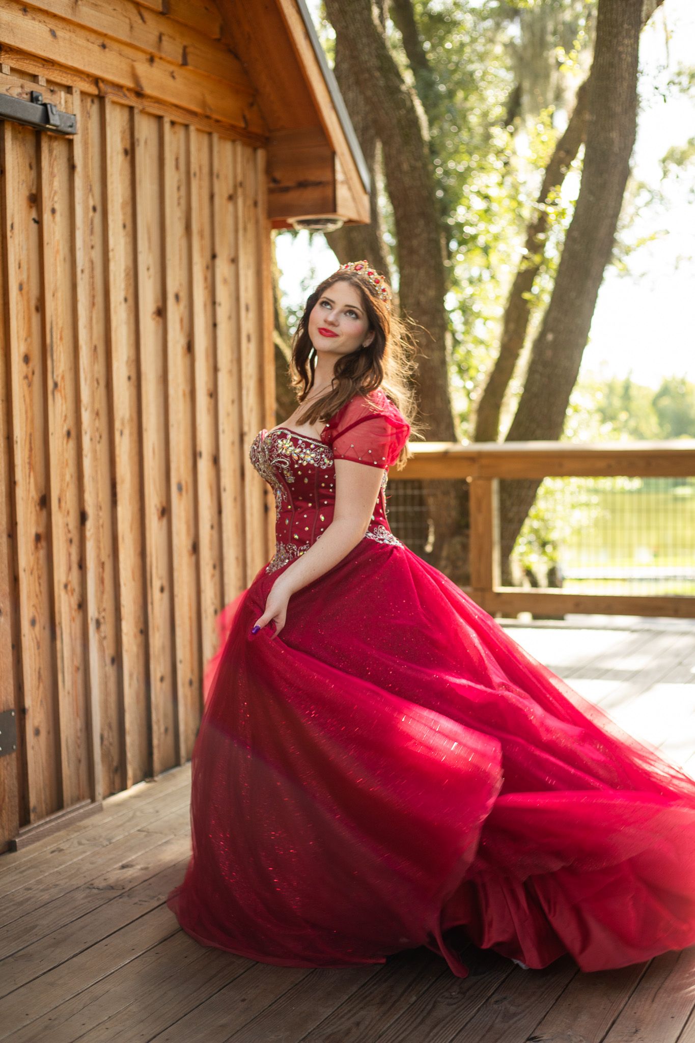 Dramatic red tulle gown with crystal details captured in motion inside a wooden structure.
