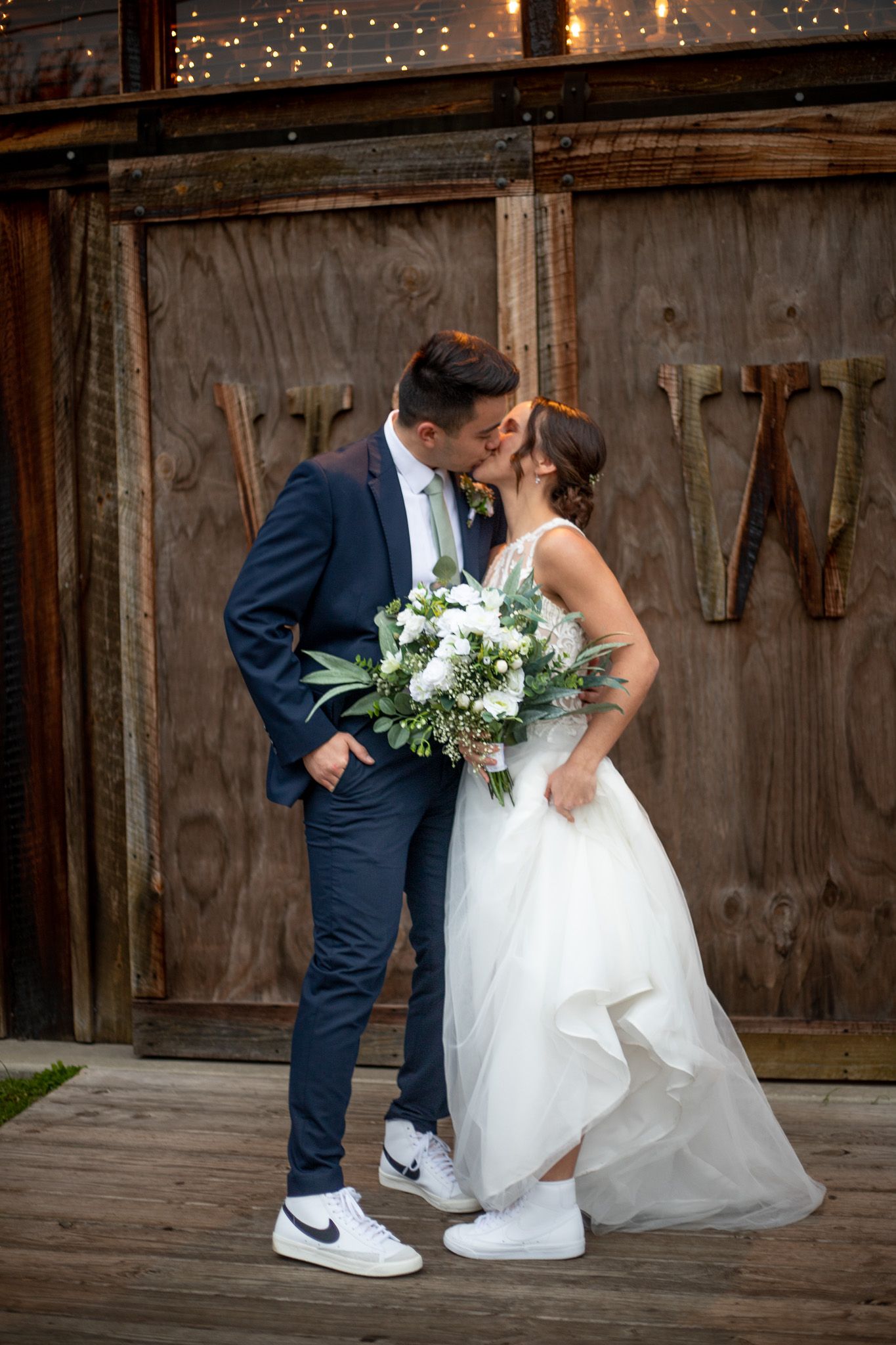 Romantic couple moment captured with string lights in rustic barn setting.