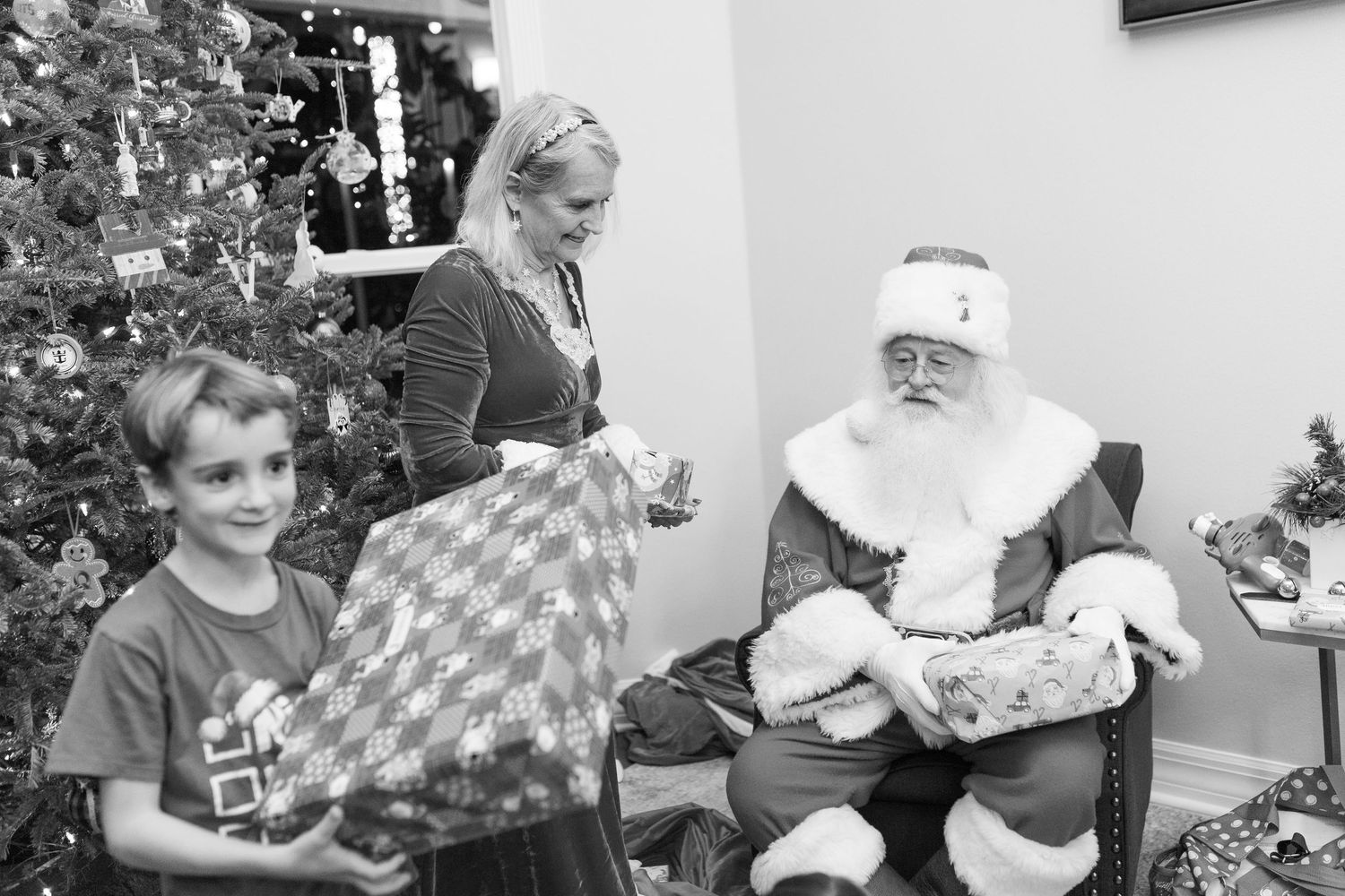 Children visit with Santa Claus near a decorated Christmas tree during a festive holiday gathering.