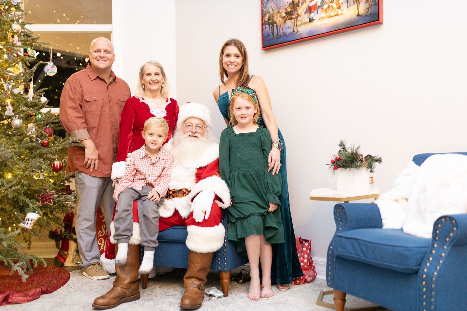 Christmas scene with decorated tree, blue armchair and holiday decorations.