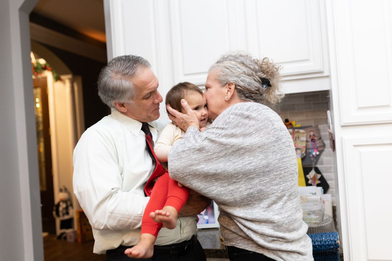 Family sharing tender moment with baby during Christmas celebration.