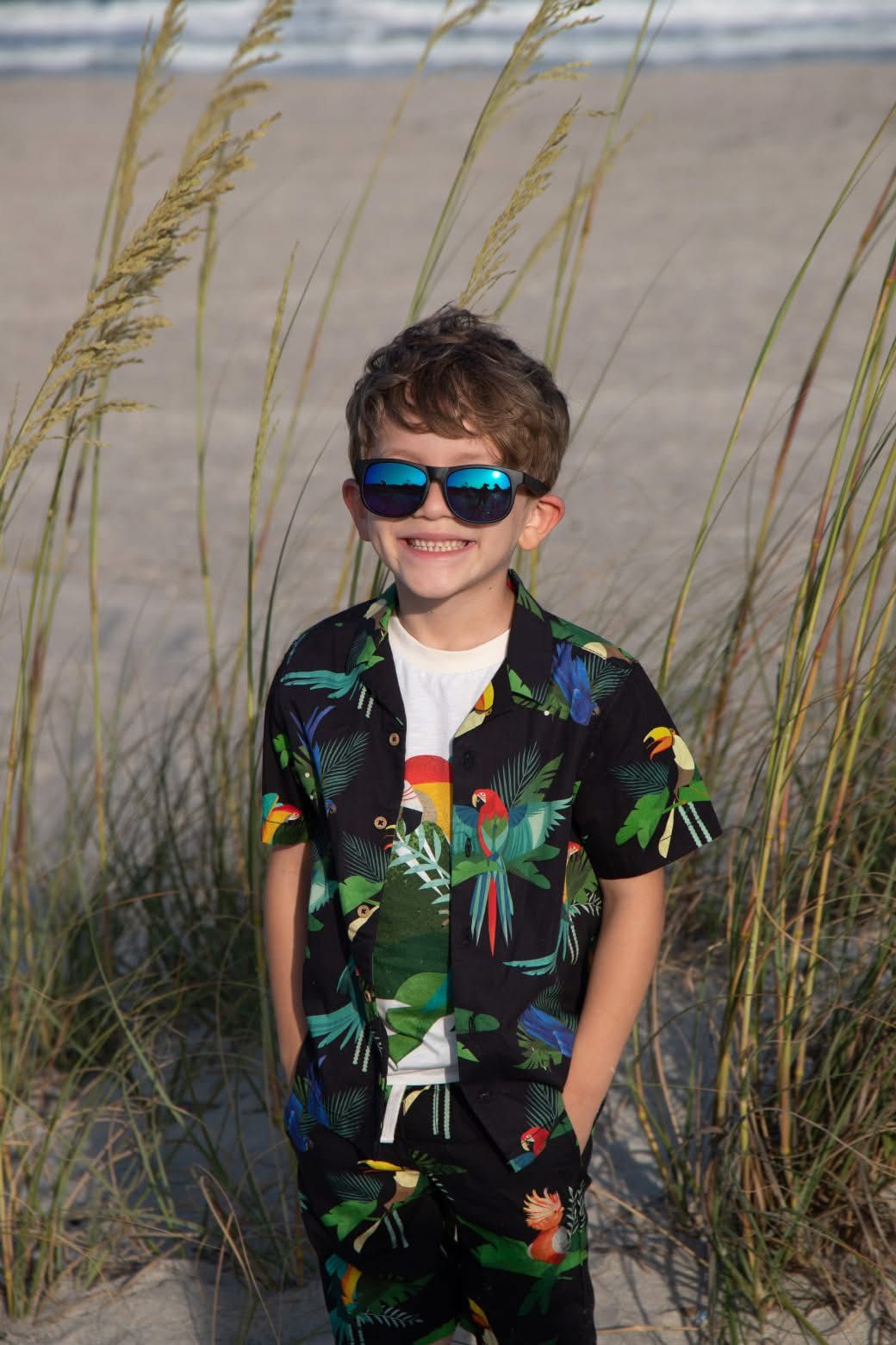 Beachside portrait with tropical print shirt and sunglasses among swaying sea oats.