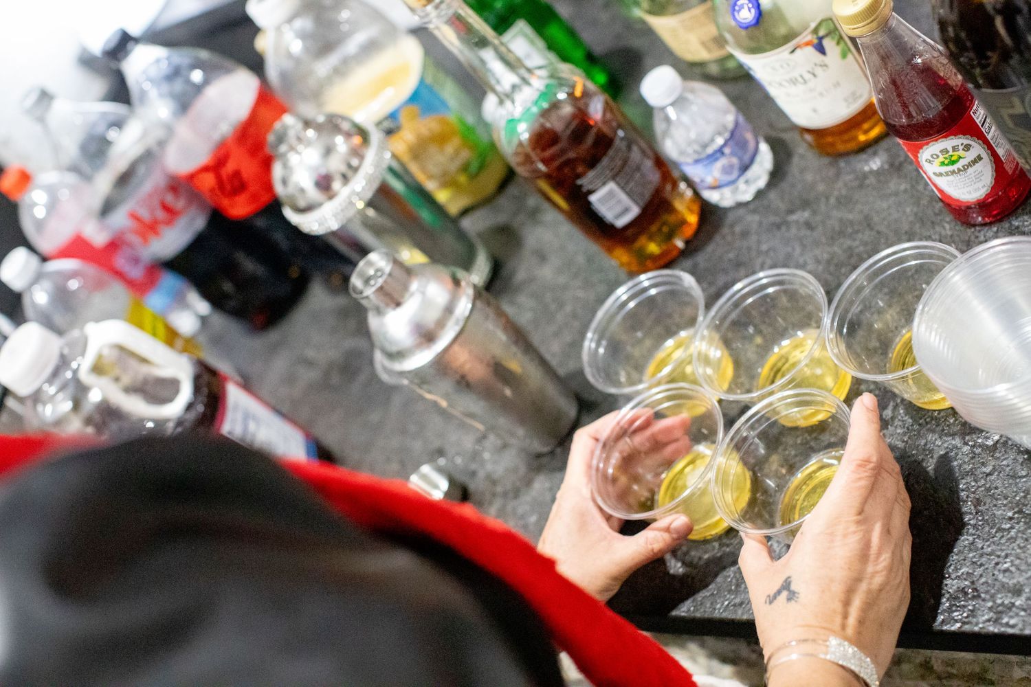 Various drinks and cocktails lined up on a bar counter during a party.