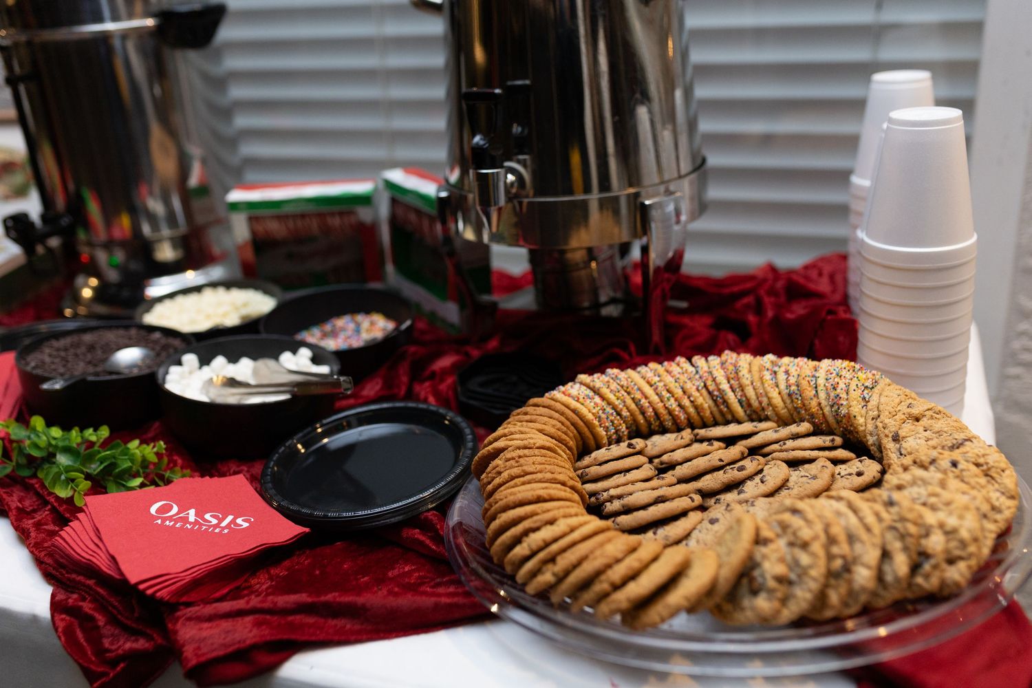 Buffet table spread with cookies and snacks on a red tablecloth.