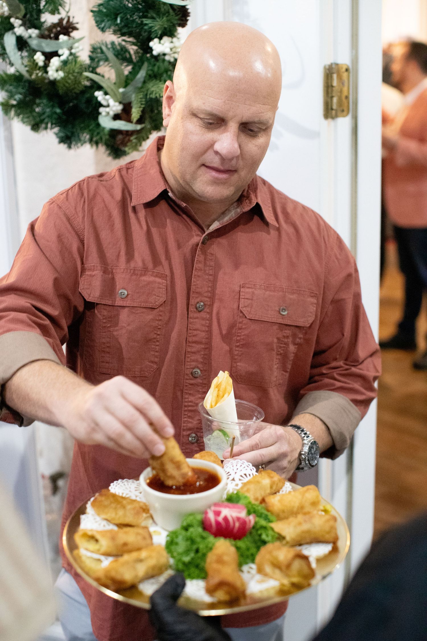 Person in brown shirt serving appetizers at a holiday party.