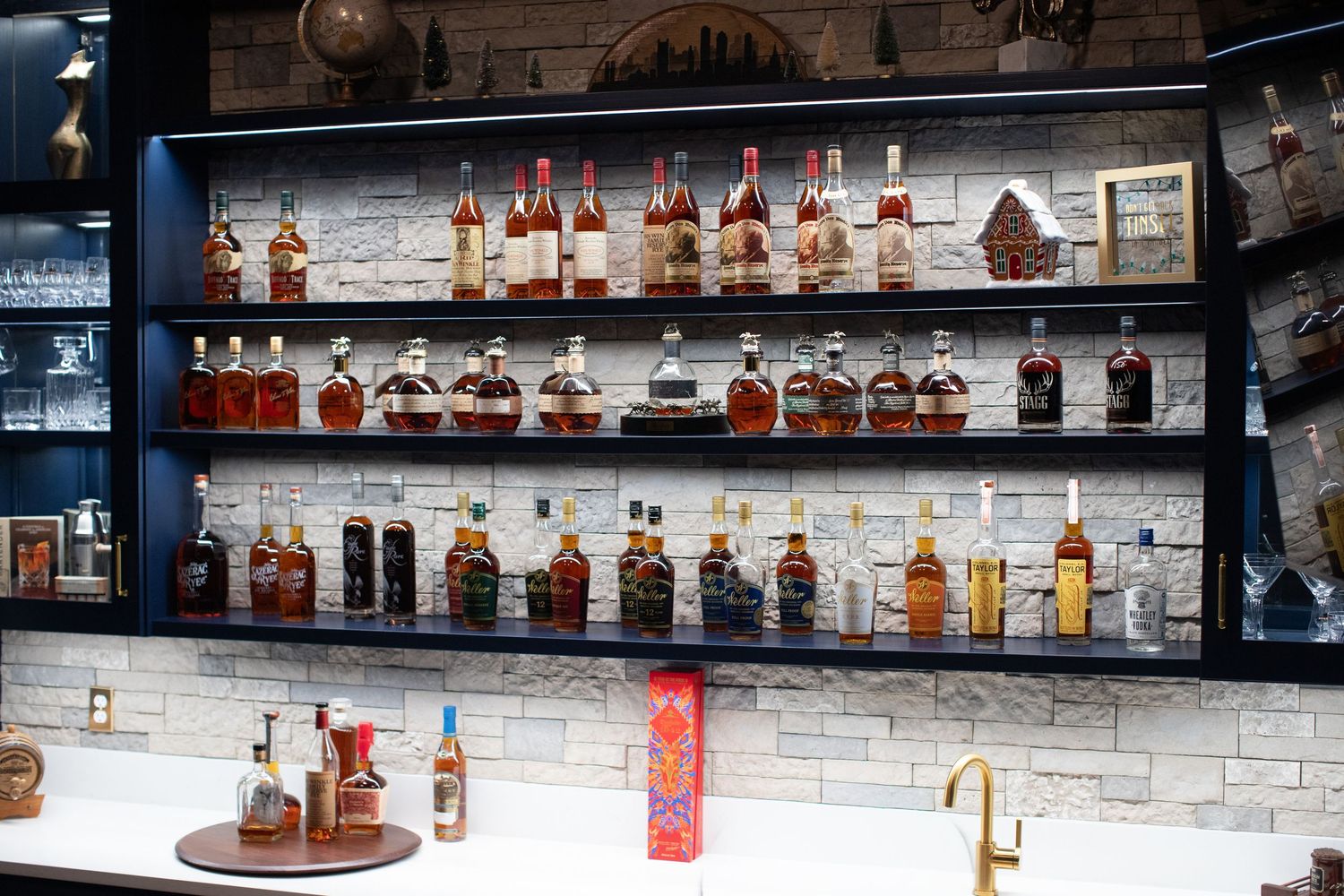 Extensive collection of bourbon bottles displayed on illuminated bar shelves.