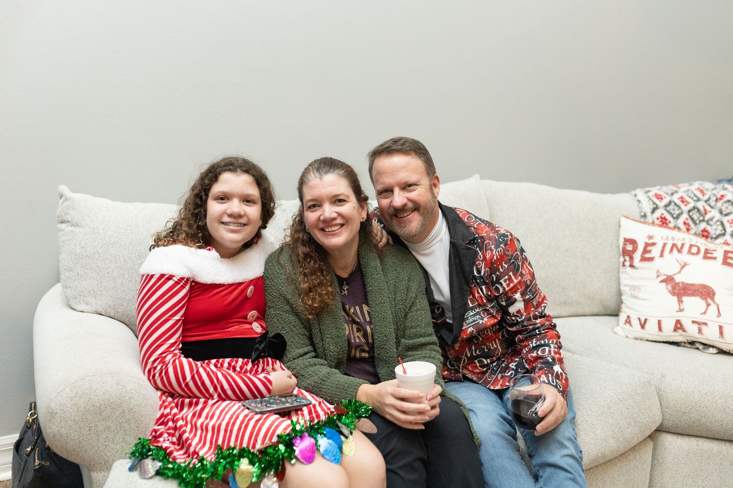 Friends gathered on a couch sharing holiday cheer during a Christmas celebration.