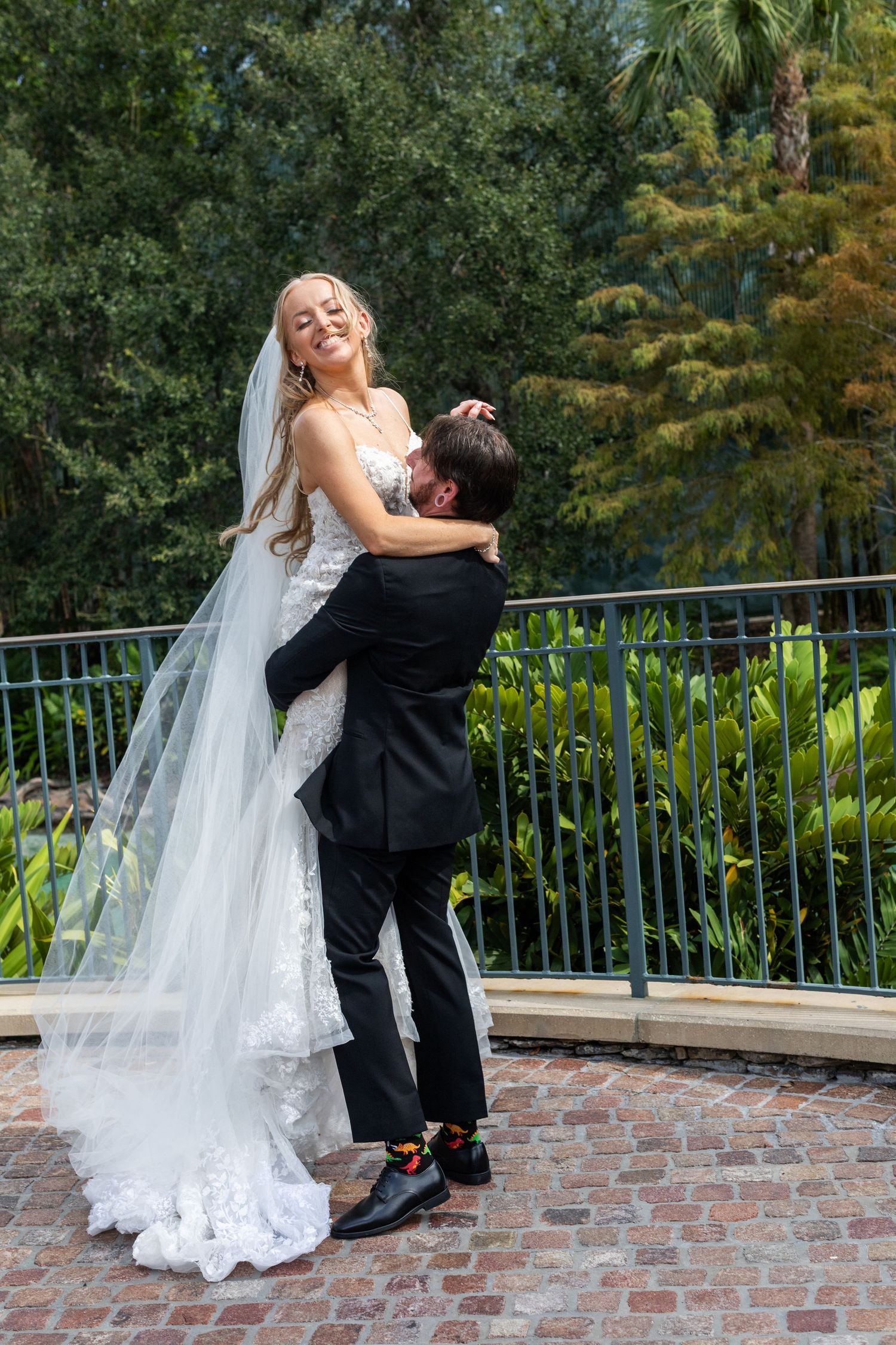 Candid wedding moments captured on a brick terrace with tropical landscaping in the background.