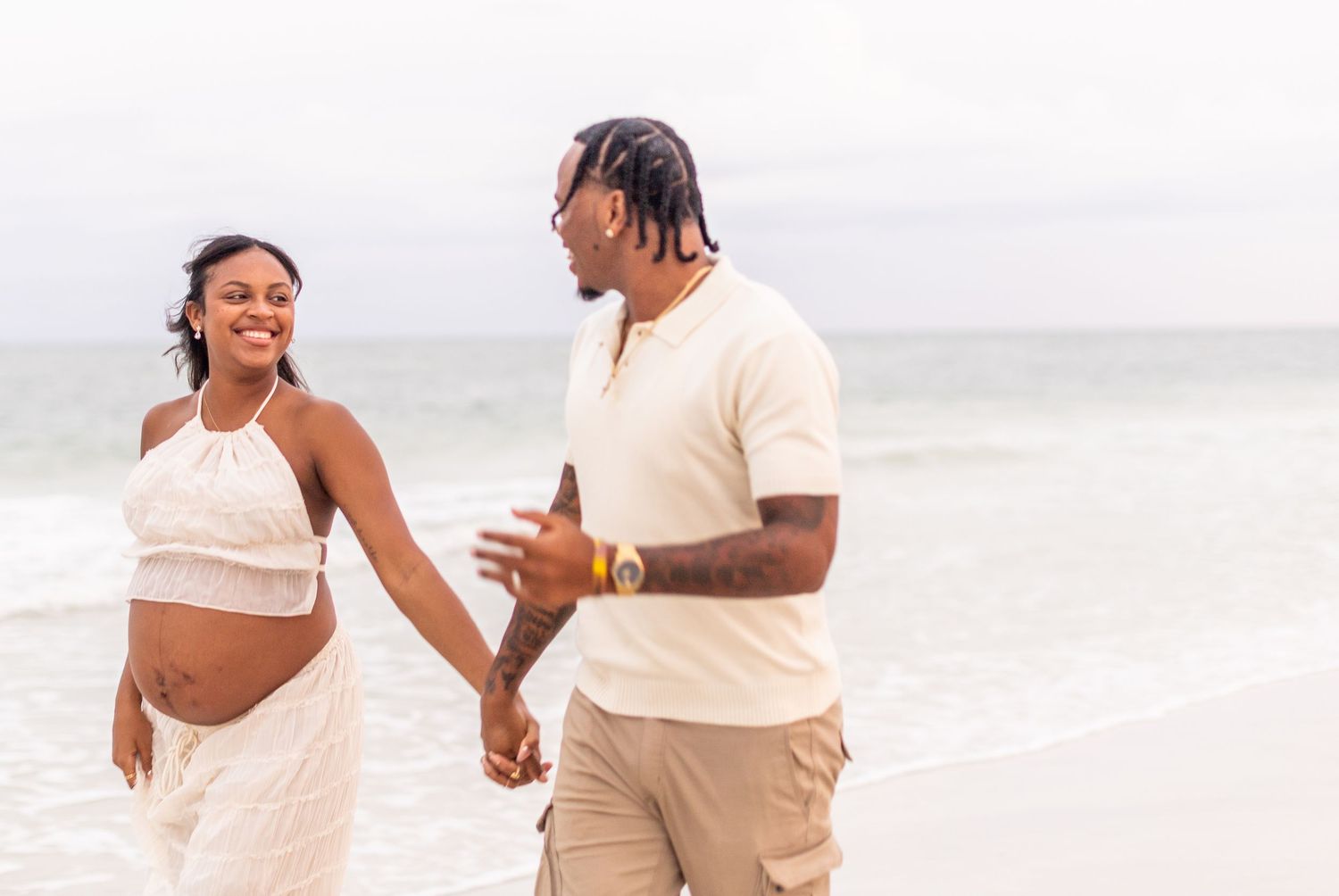 A couple shares a romantic moment on the beach during their maternity photoshoot.