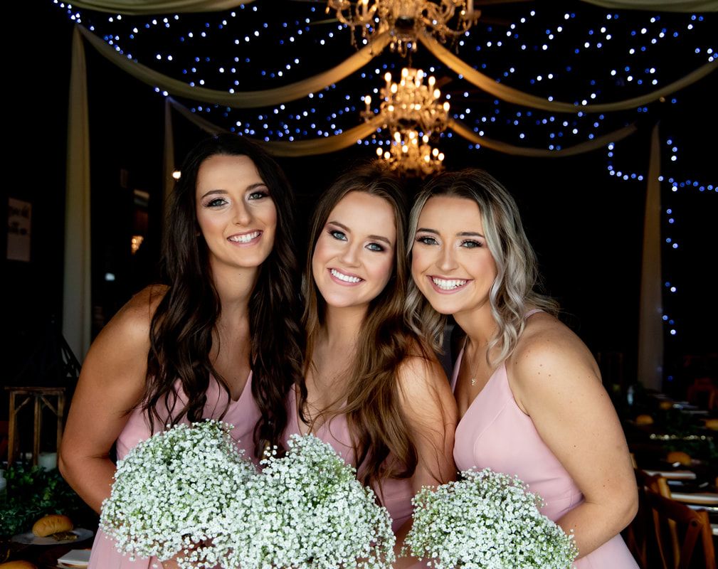 Wedding party celebration under sparkling lights with bridesmaids in matching dresses.