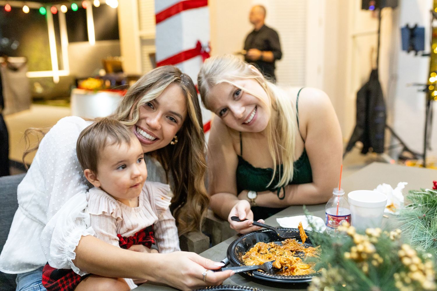 A holiday gathering with people seated at a decorated table enjoying food and conversation.