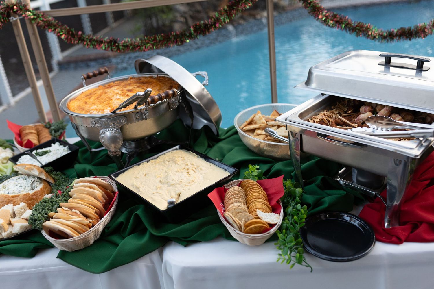 Catering spread with food and drinks displayed alongside a pool area.