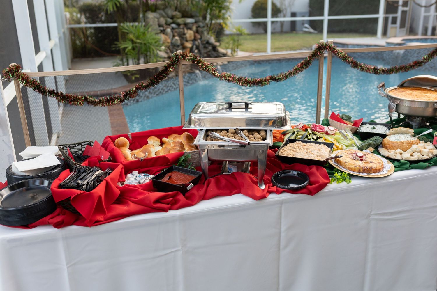 Long buffet table with appetizers and red decorations set up for catering.