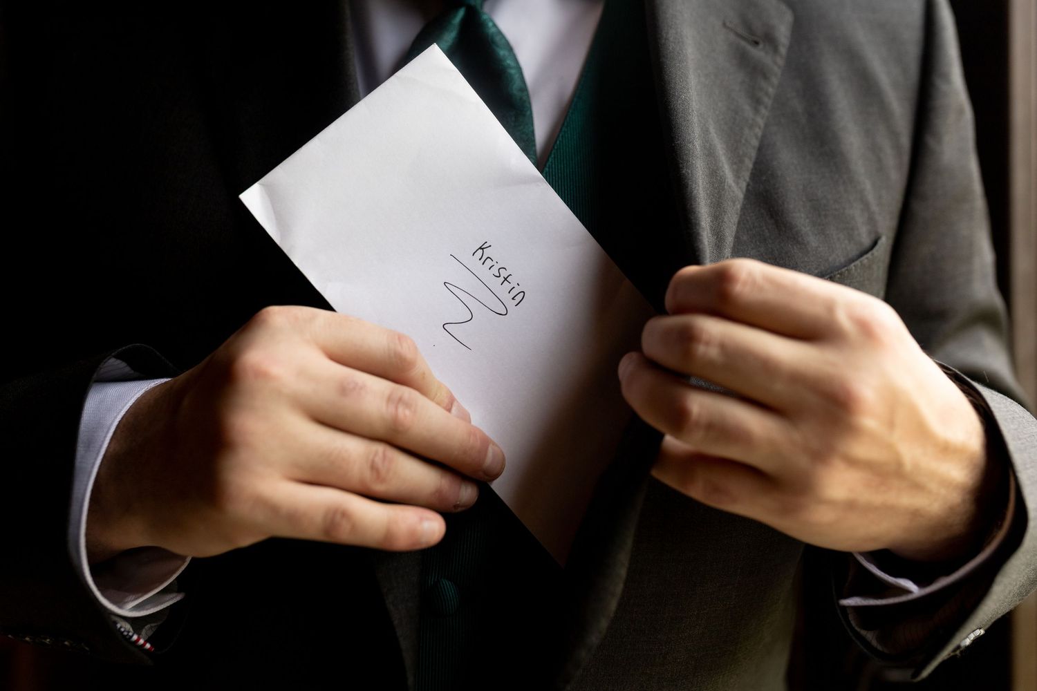 Close-up of hands holding wedding vows written on elegant paper.