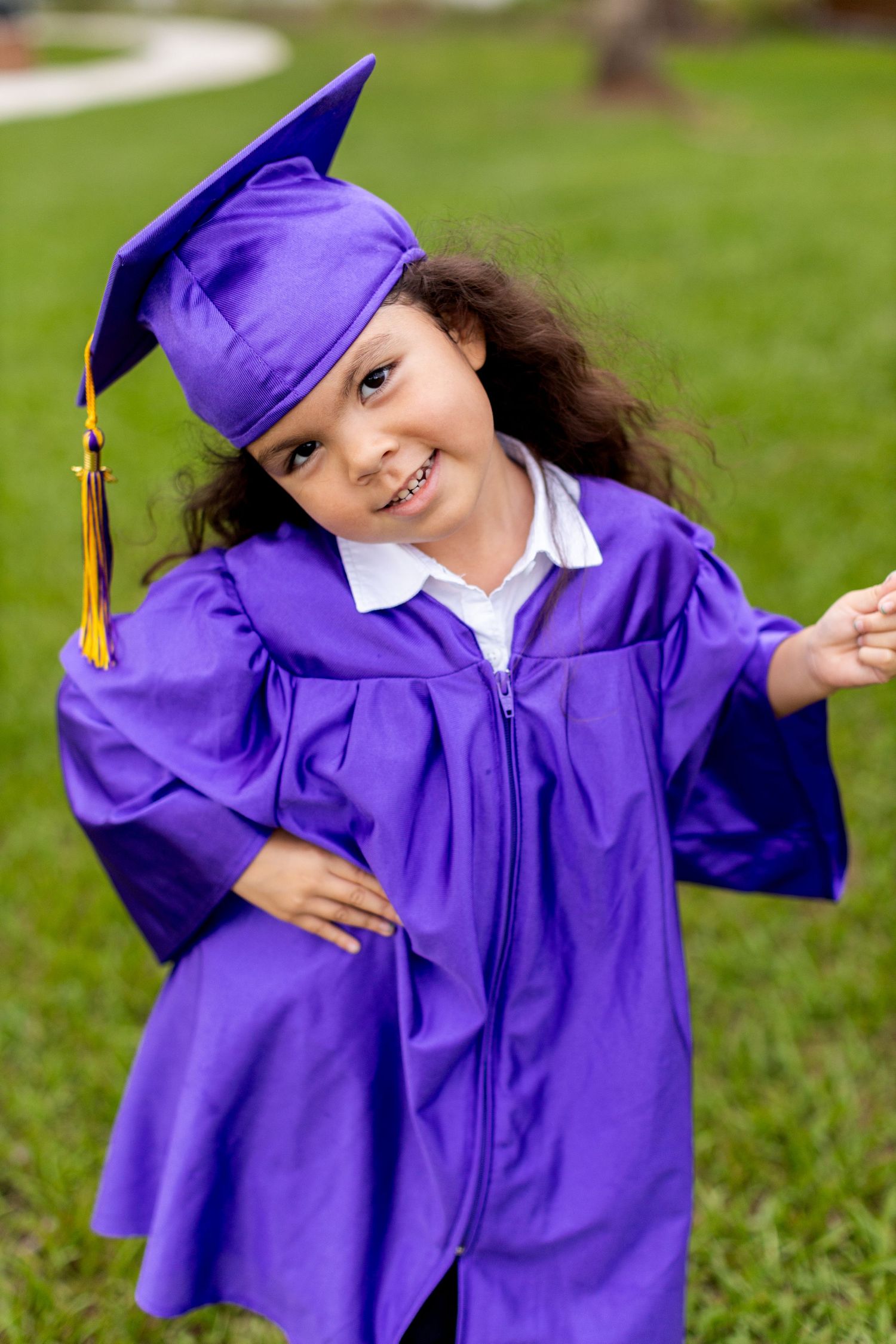 Candid sequence of someone in purple graduation attire making silly poses on grass.
