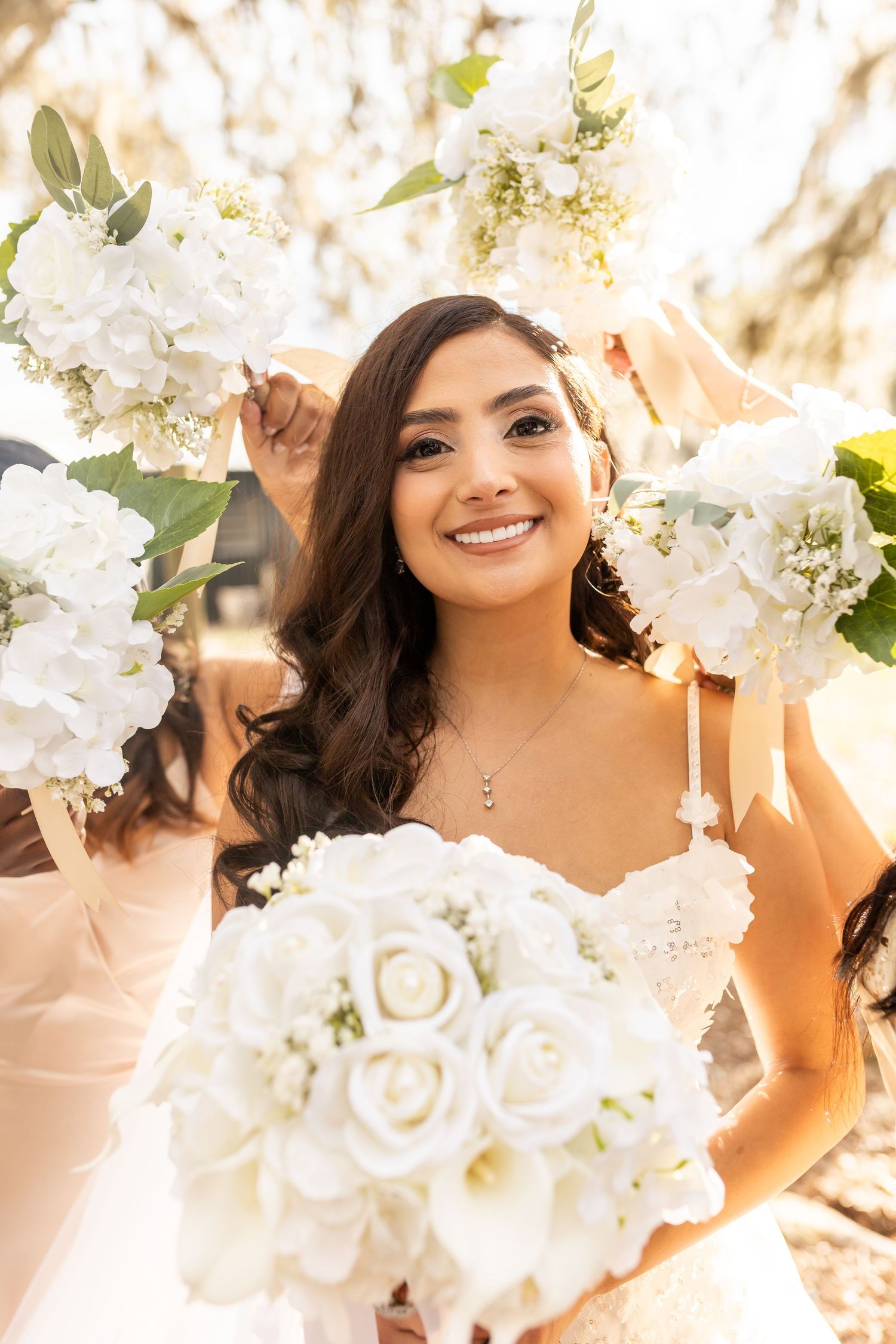 White floral arrangements frame a bridal portrait with soft natural lighting.