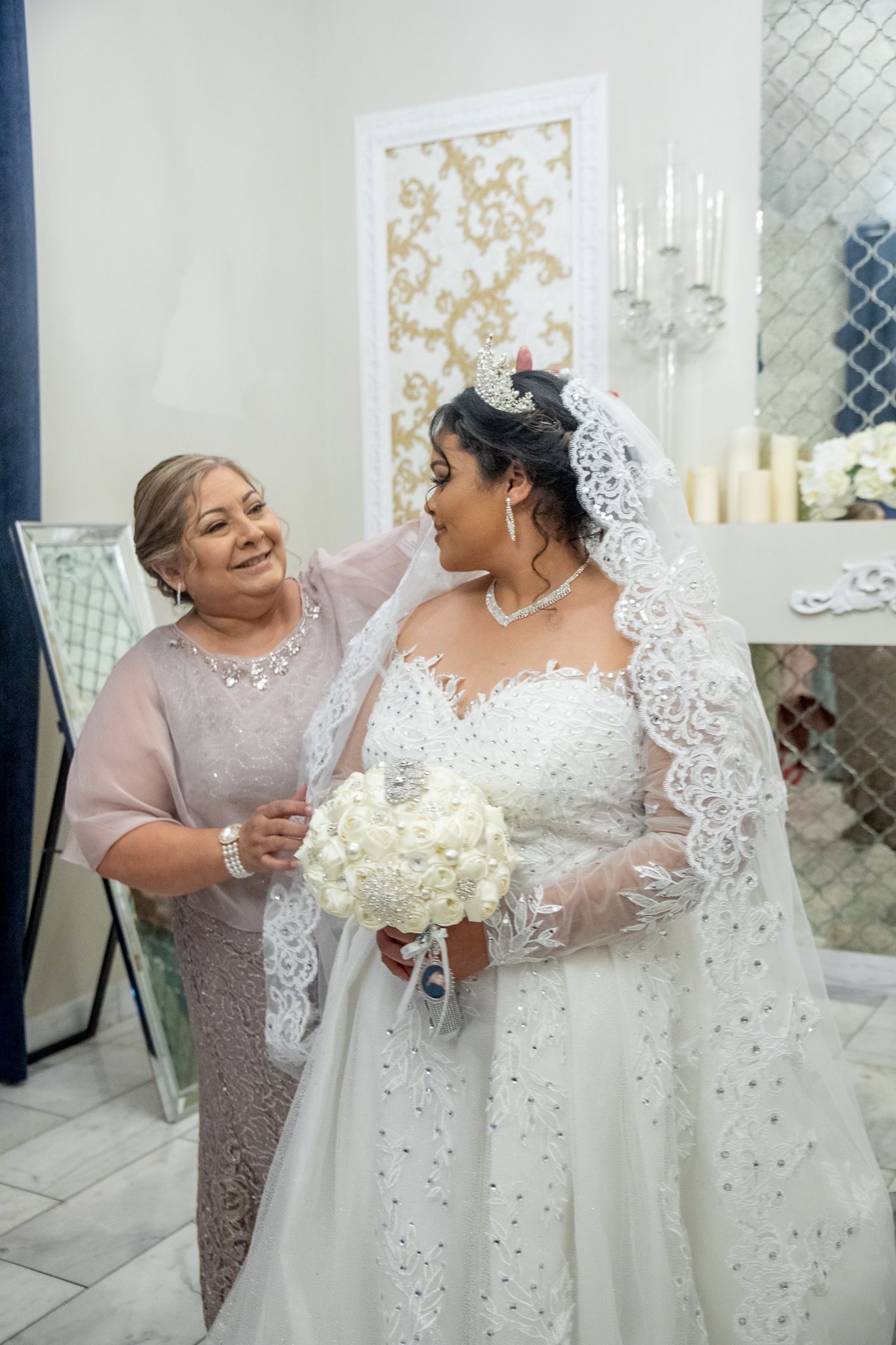 Elegant wedding celebration in white room with crystal chandelier and ornate decorations.