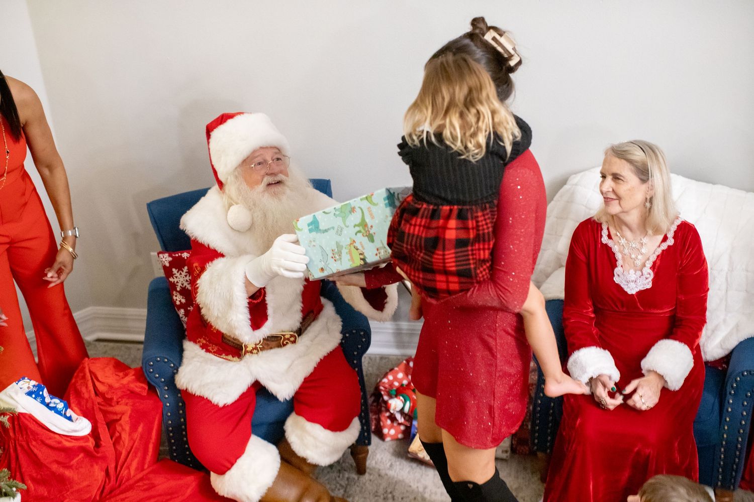 Holiday celebration with Santa Claus and guests in festive red attire.