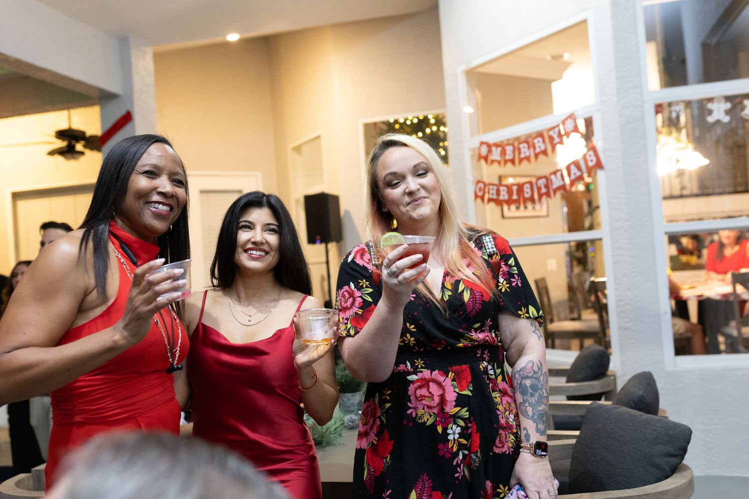 Women in red and black outfits dancing together at a holiday party.