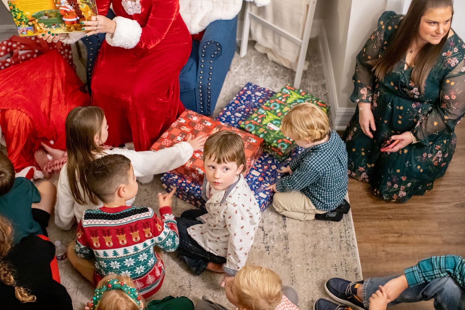 Children in holiday attire sitting and interacting during a Christmas celebration.