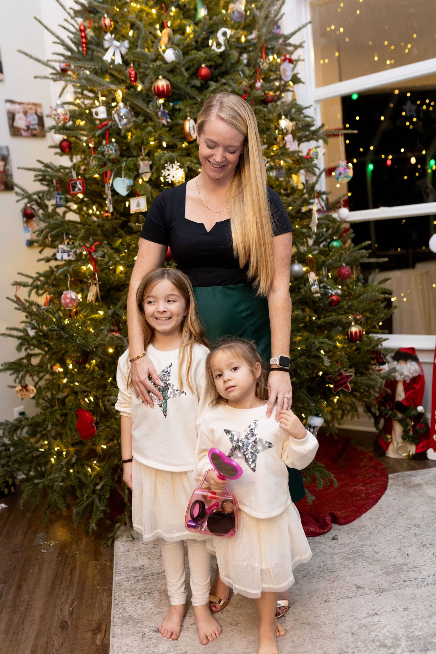 Beautifully decorated Christmas tree with family posing in front.