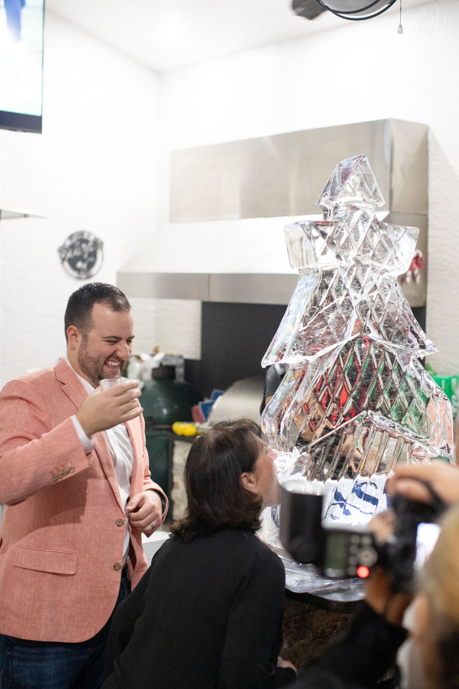 Person in salmon blazer examines an ice sculpture display at an event.