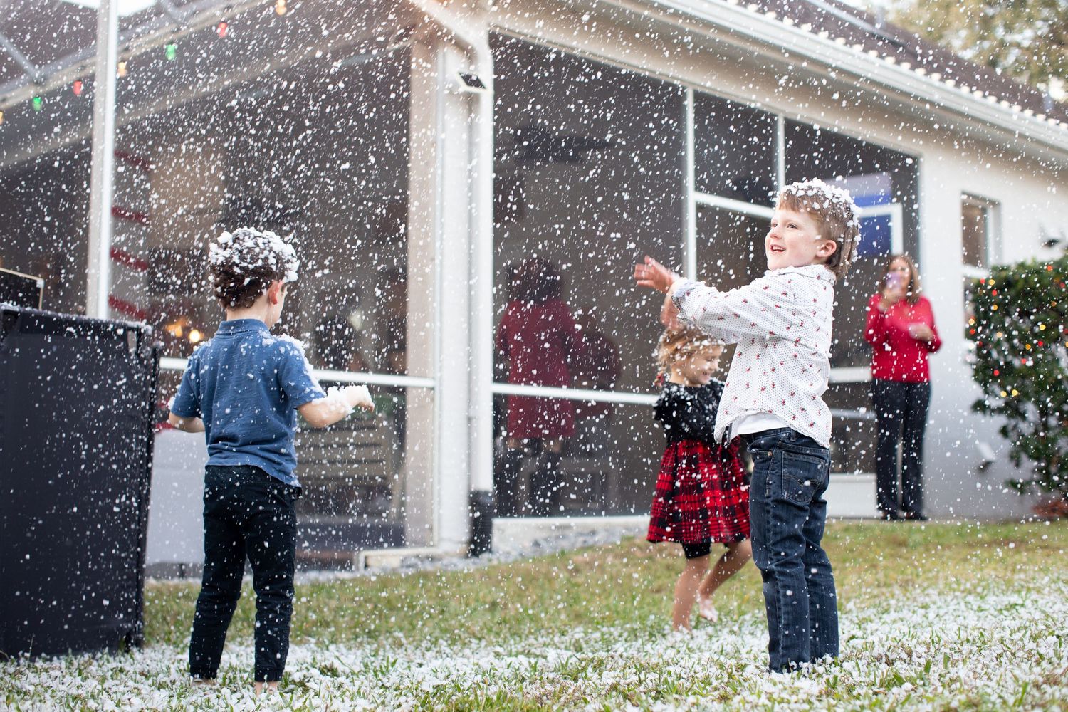 White artificial snow falling outside a building during a festive event.