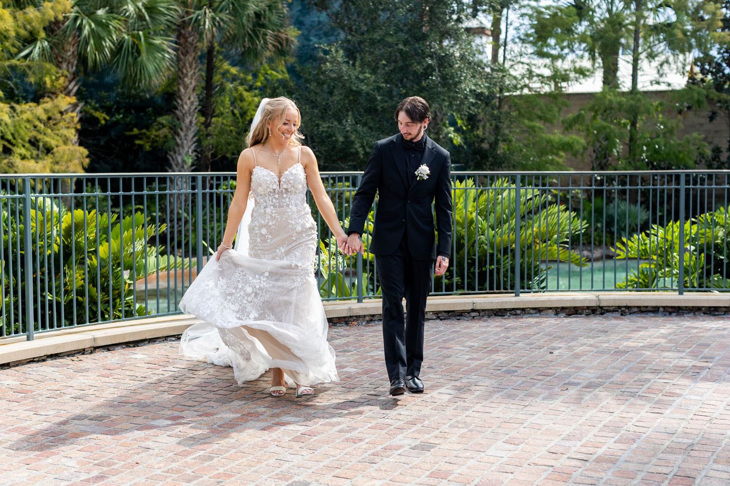 Wedding couple sharing candid moments on a scenic outdoor terrace with tropical foliage.