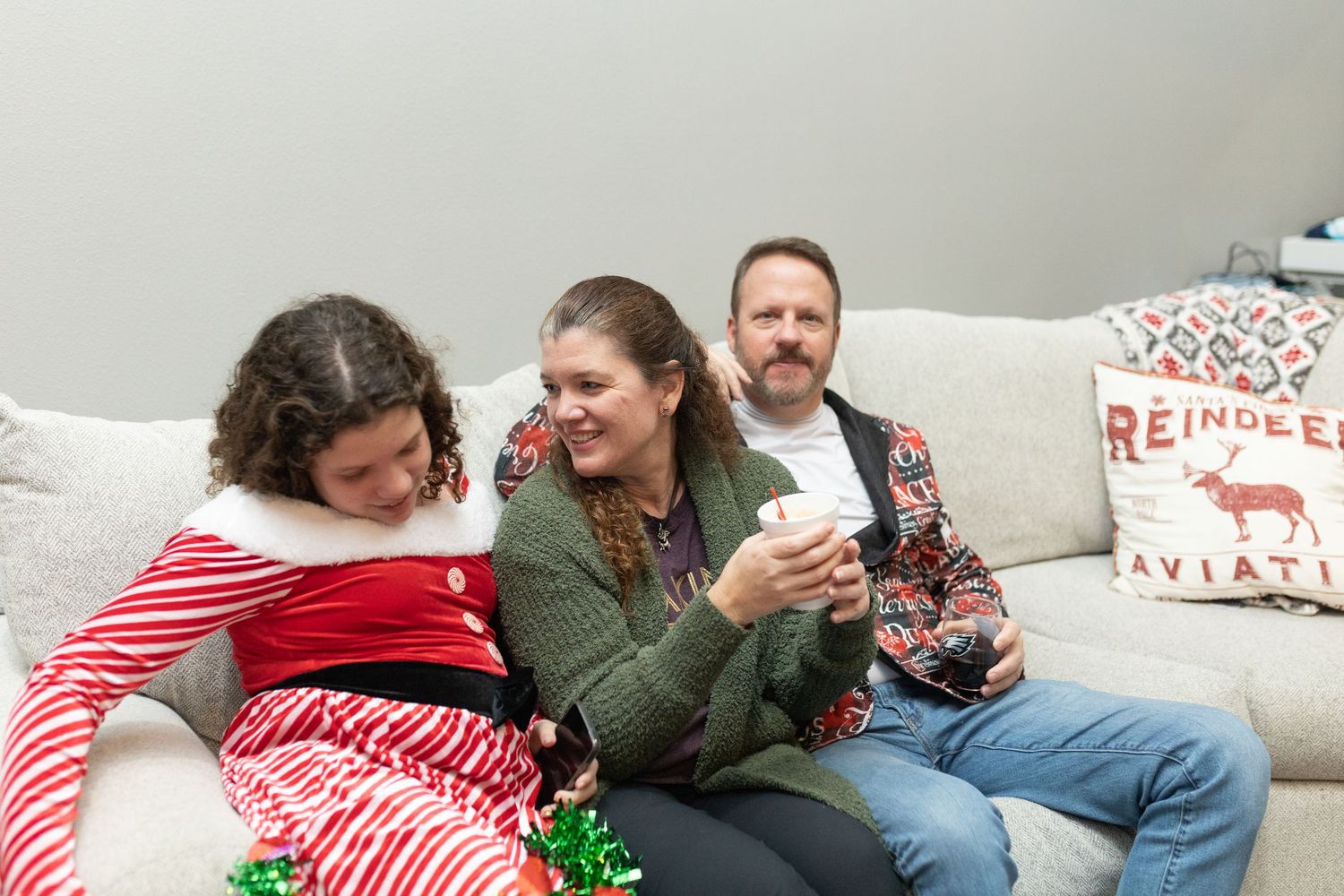 Guests relaxing on couches at a casual holiday gathering with decorative pillows.