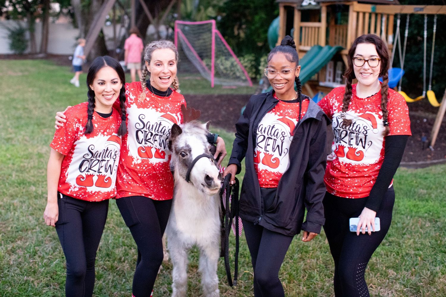 Group wearing matching red holiday sweaters posing with a dog outdoors.