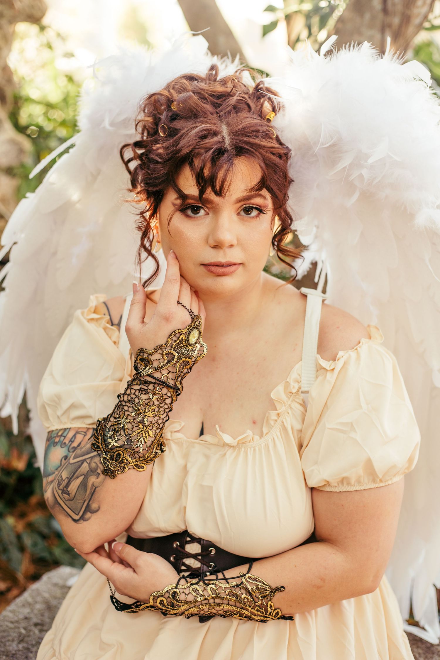 Dreamy outdoor photoshoot with white feathered wings and vintage-inspired cream dress.