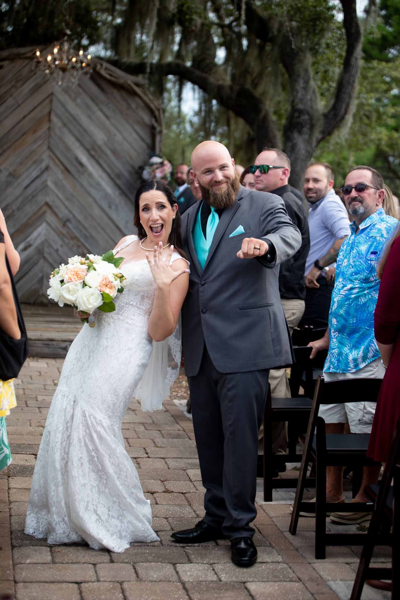 Candid moments of wedding guests enjoying festivities on a stone patio under hanging moss.