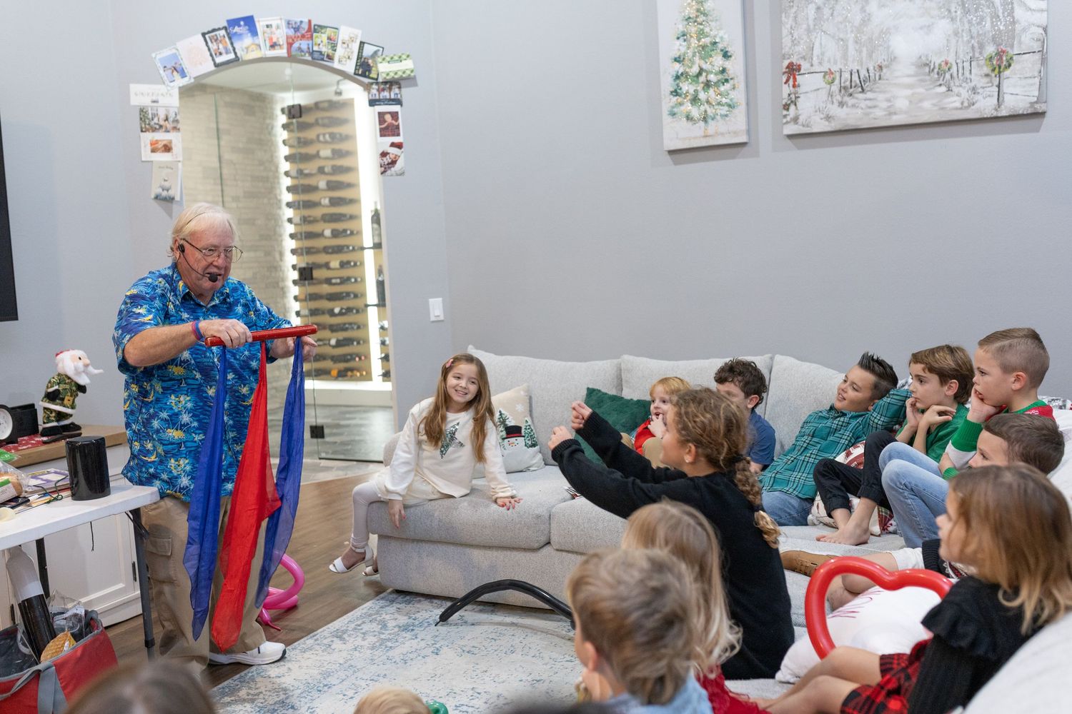 People gathered in a room for a holiday event with artwork displayed on gray walls.