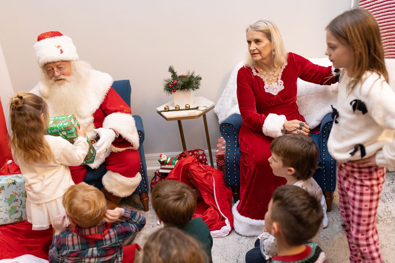 Children line up to meet Santa Claus at a Christmas gathering with festive decorations.