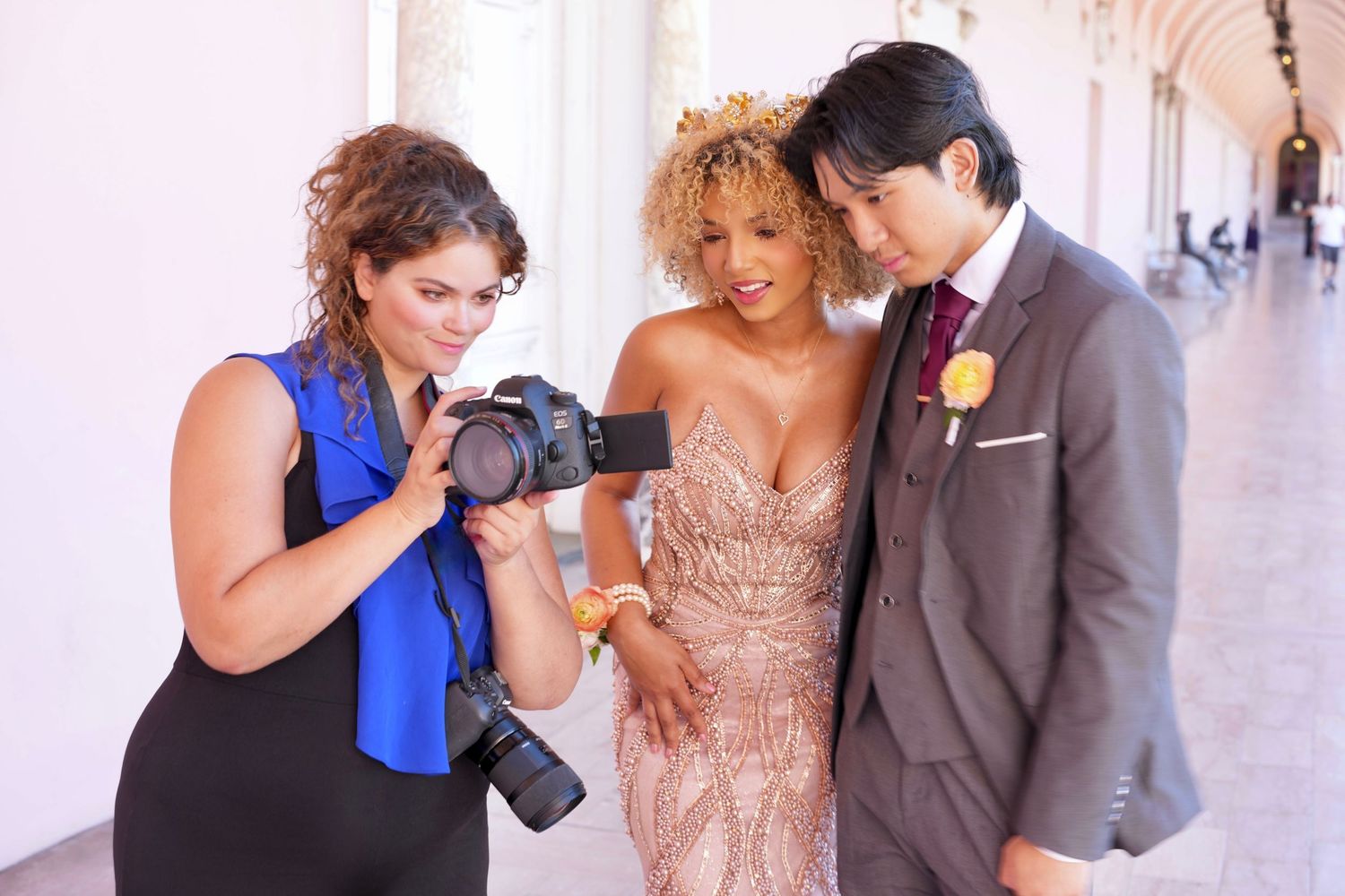 Wedding photographer shows bride and groom photos on camera at elegant venue.
