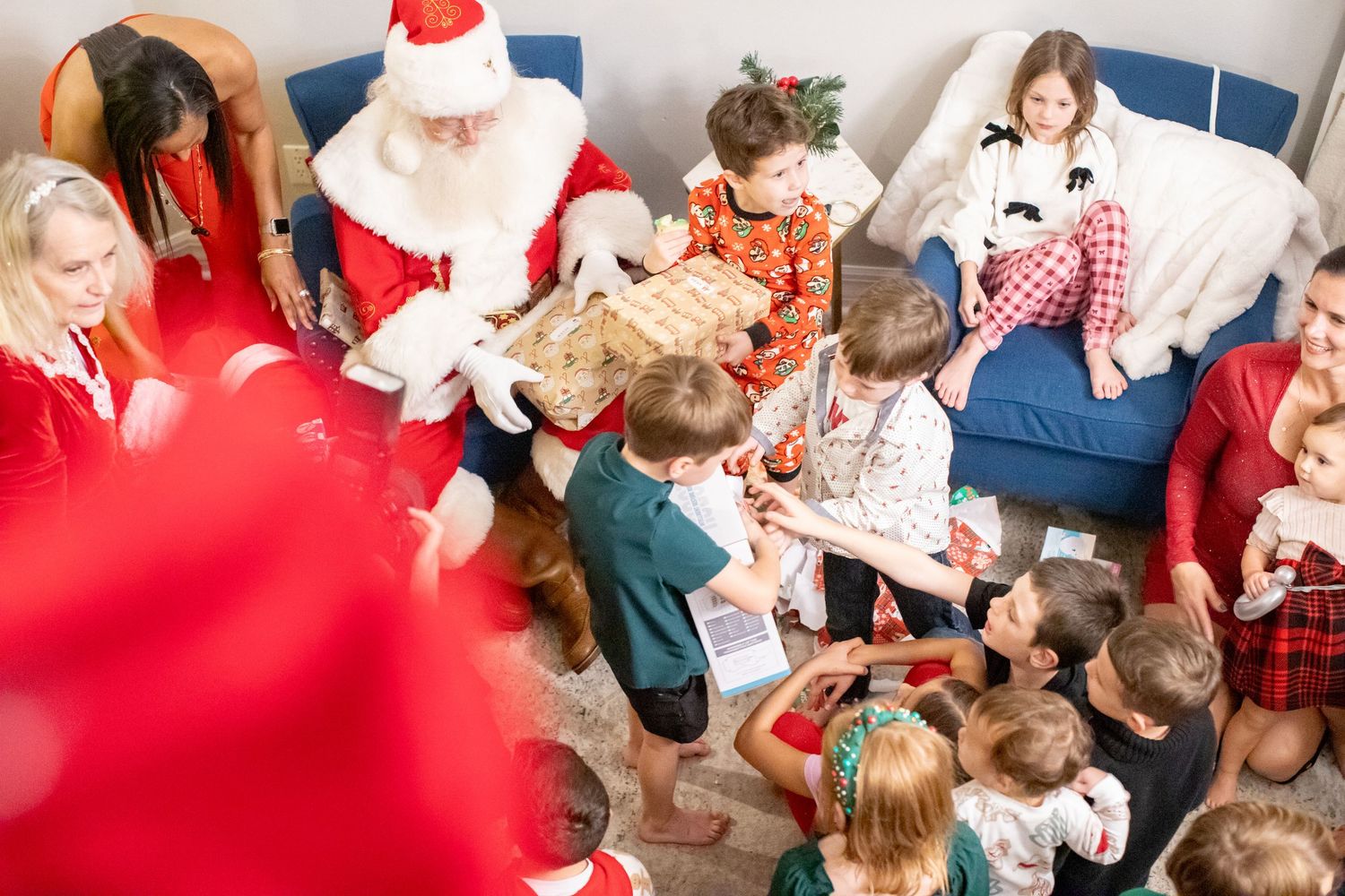 A holiday gathering shows children sitting around a decorated room with festive decorations.