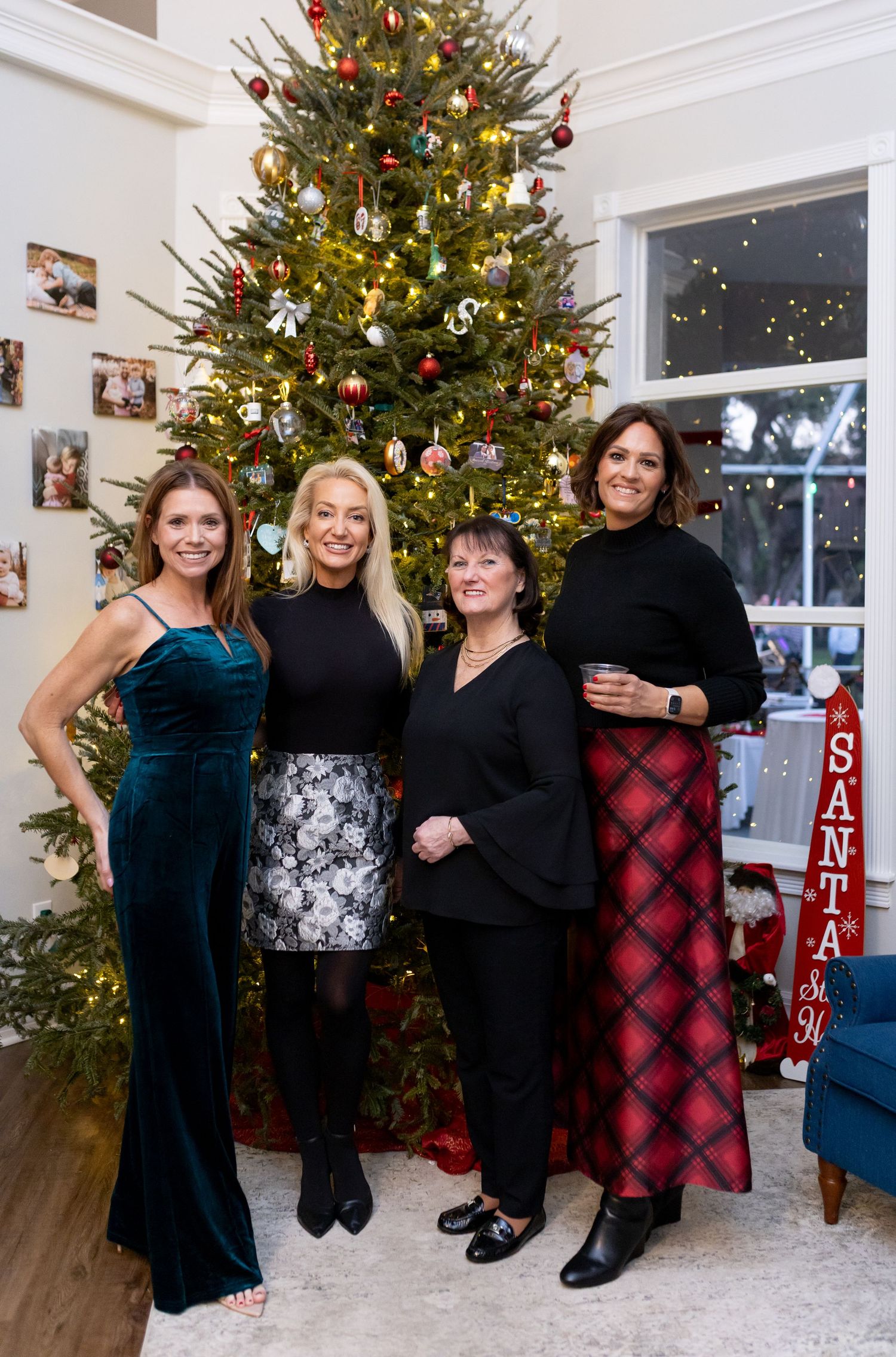 Group photo session in front of an elegantly decorated Christmas tree with white decor.