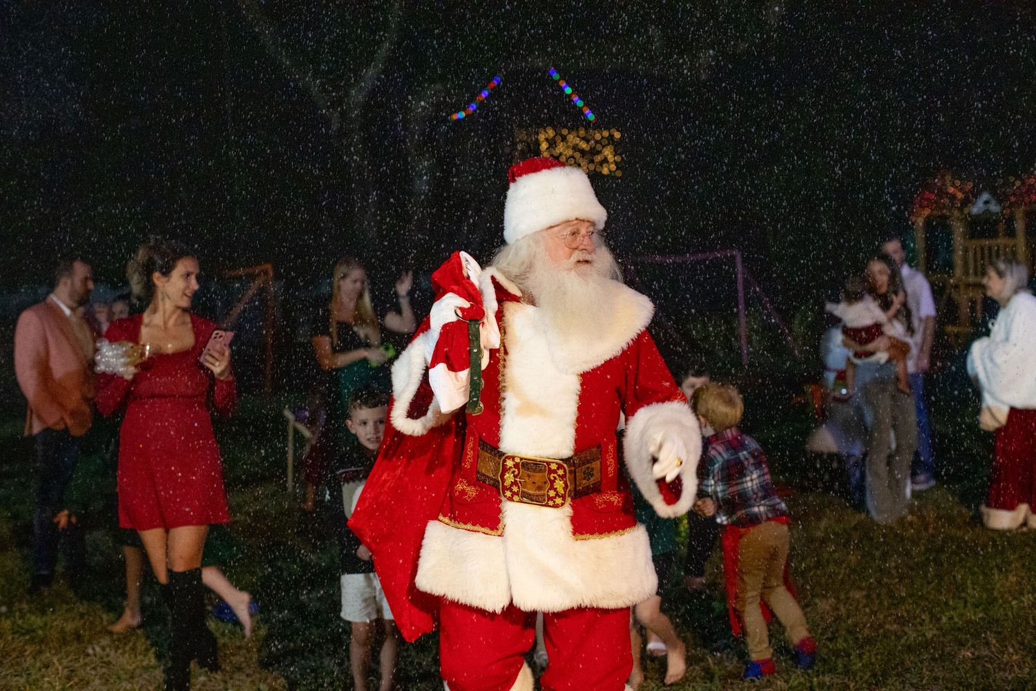 Outdoor nighttime holiday gathering with festive decorations.