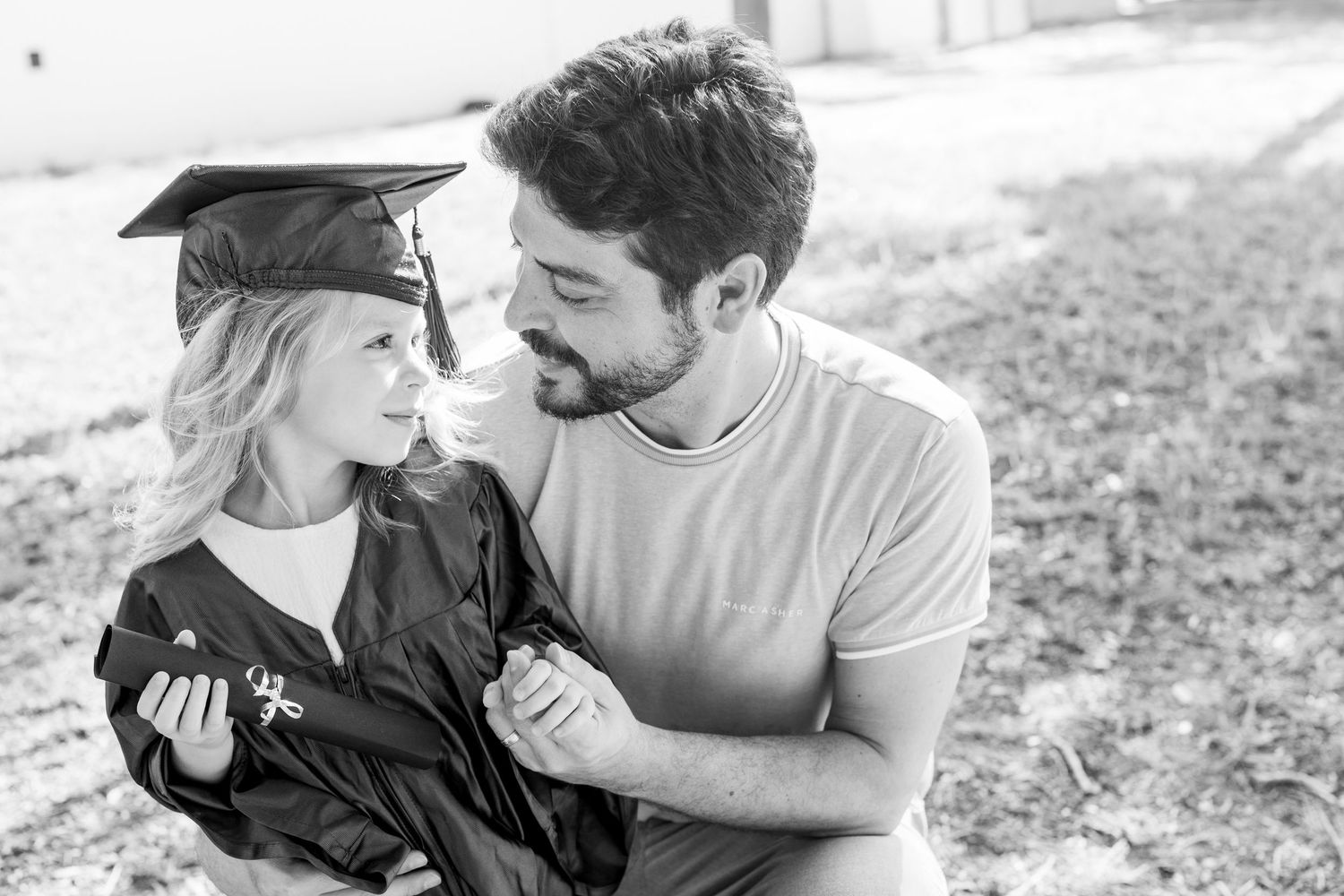 Black and white portrait of graduation celebration moment outdoors.
